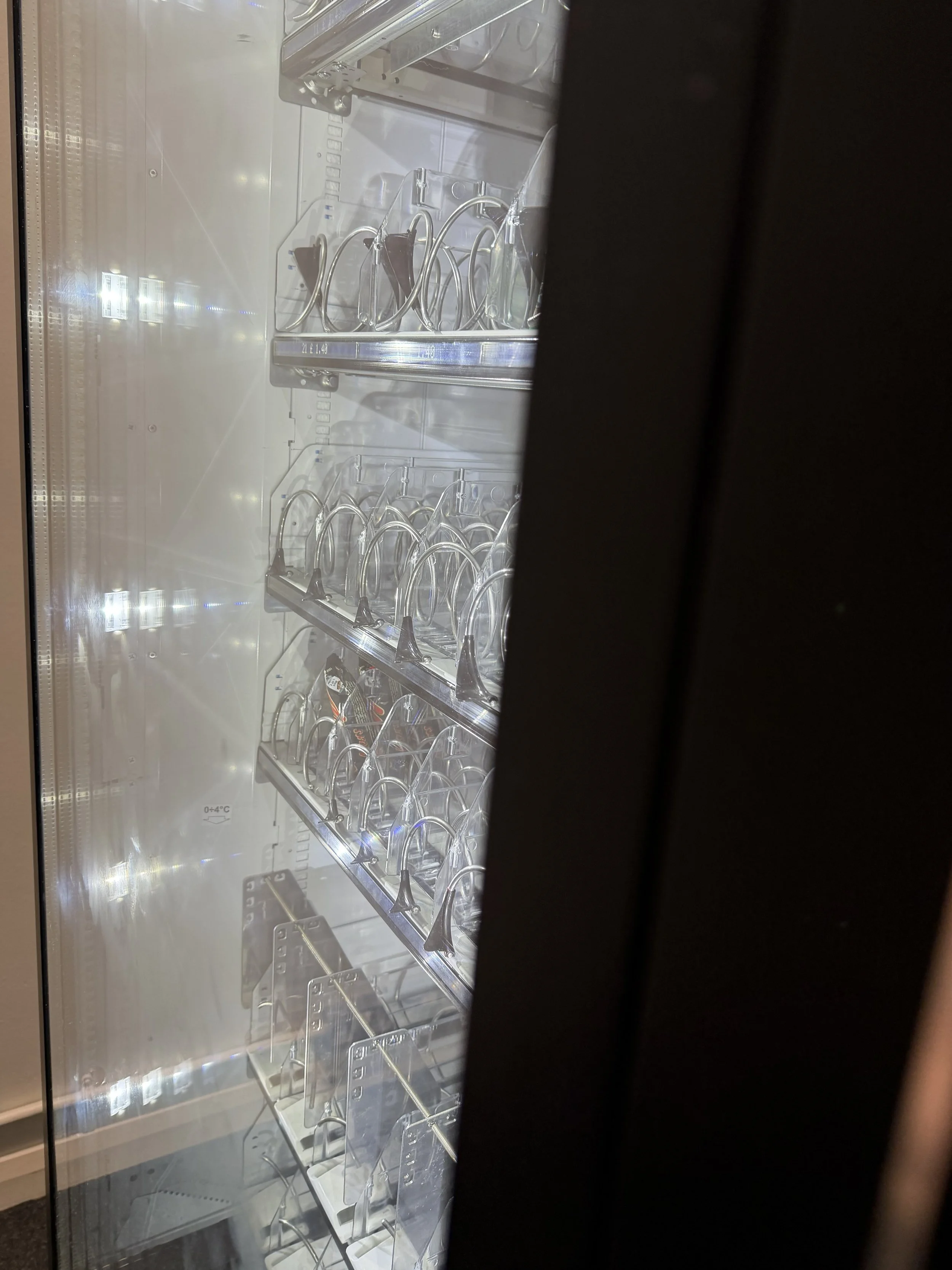 Inside a refrigerated display case containing eyeglasses on several shelves.