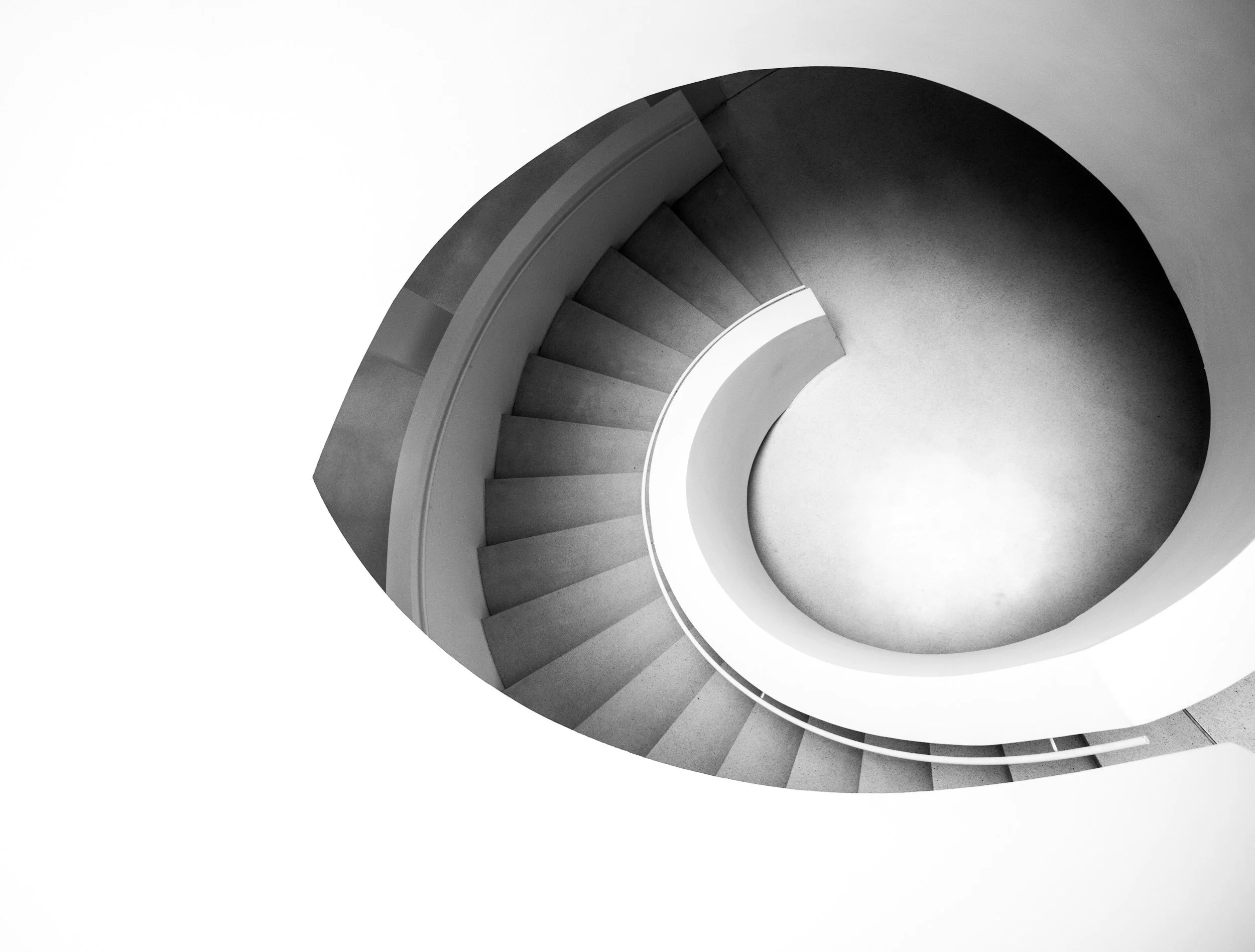 Black and white aerial view of a spiral staircase viewed from above.