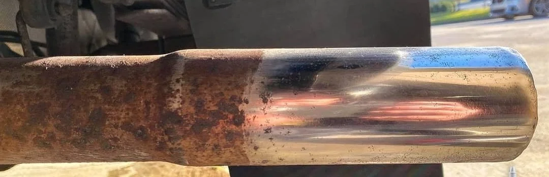 Close-up of a metal exhaust pipe, showing rust and shiny metal surface.