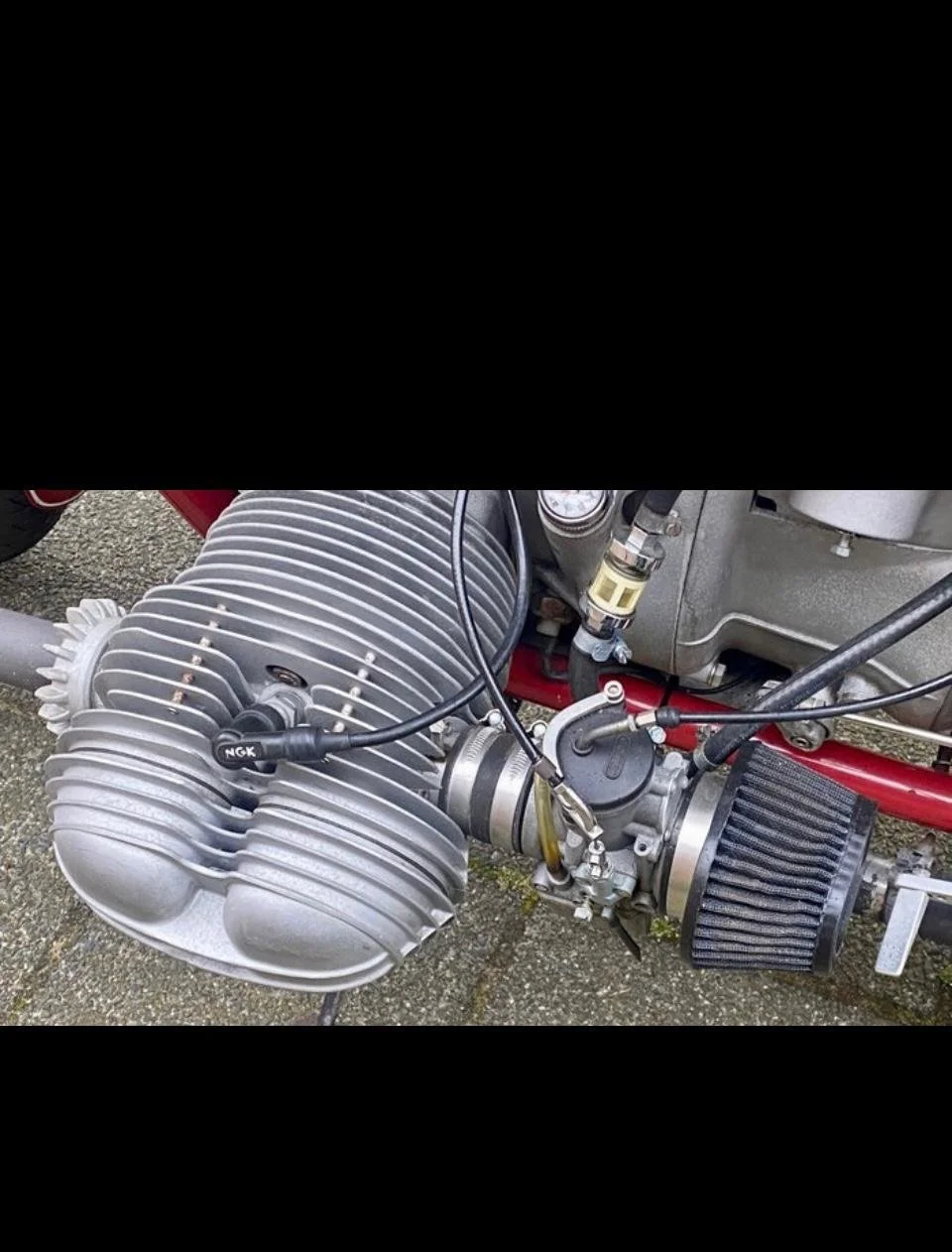 Motor de avión con cilindros en línea, filtro de aire, componentes metálicos y cables en un chasis rojo.