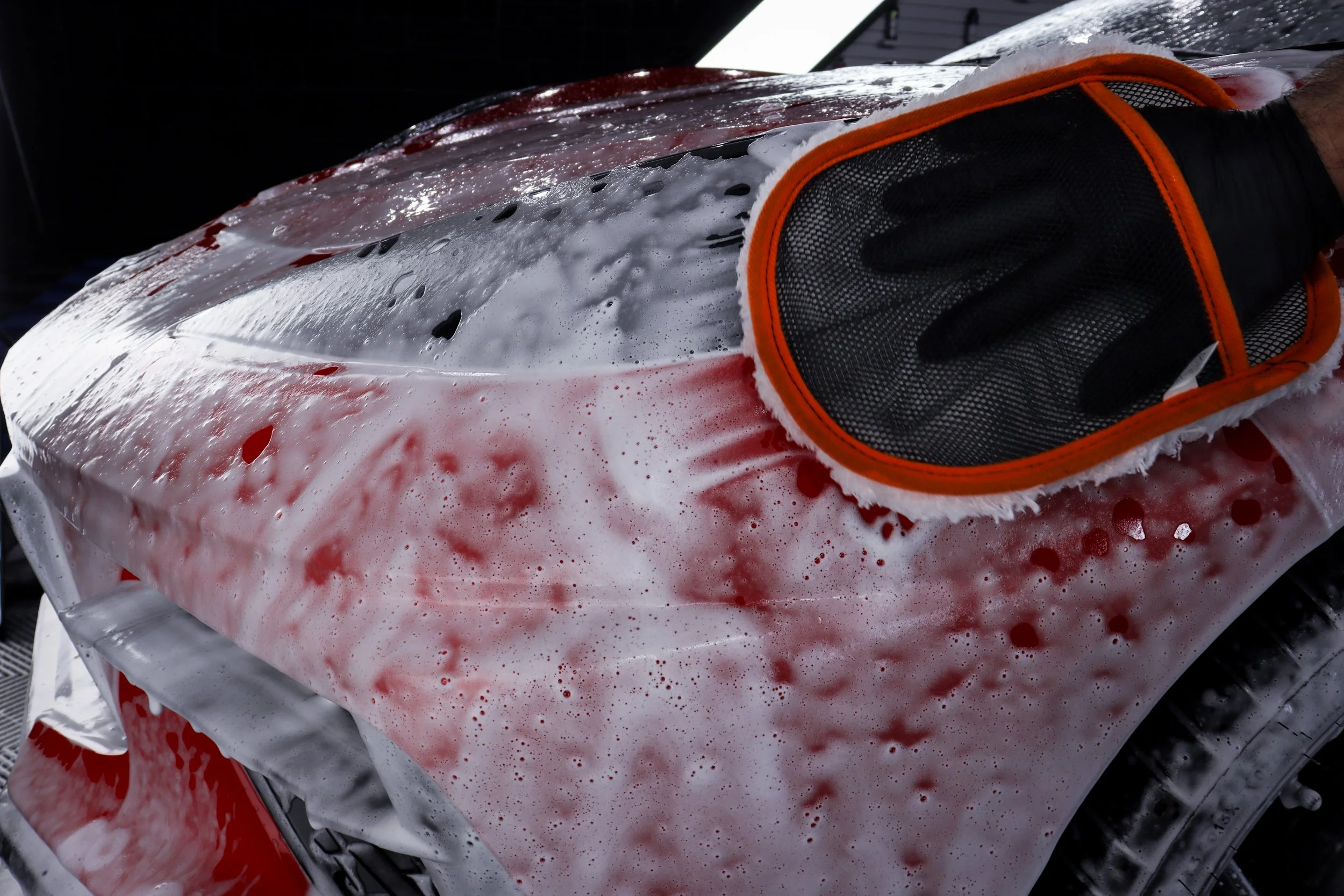 Medical personnel wearing black gloves applying foam to a person bleeding from their head, with blood on their skin and hair.