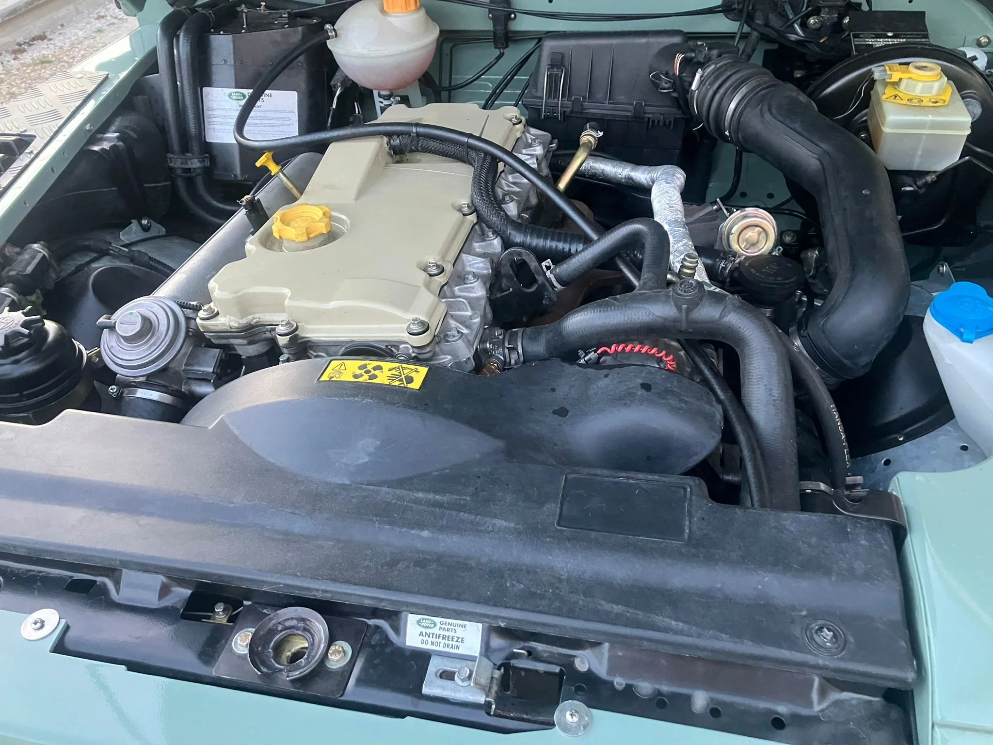 Motor de un vehículo, vistas del sistema de enfriamiento, filtro de aire, y varias mangueras y componentes mecánicos.