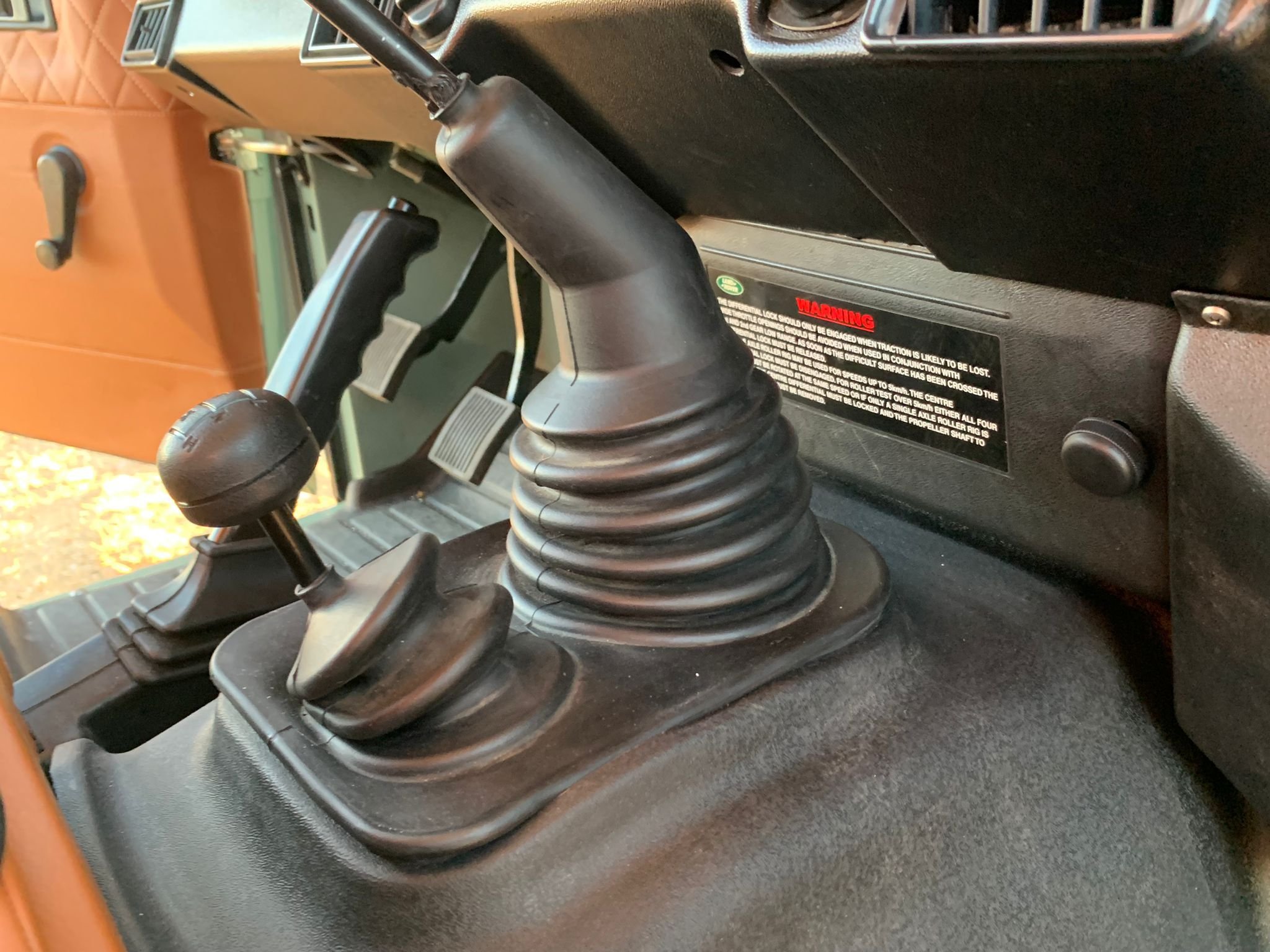 Controles del vehículo, incluyendo palanca de cambios y palanca de transmisión con fuelle de goma, en el interior de un automóvil.