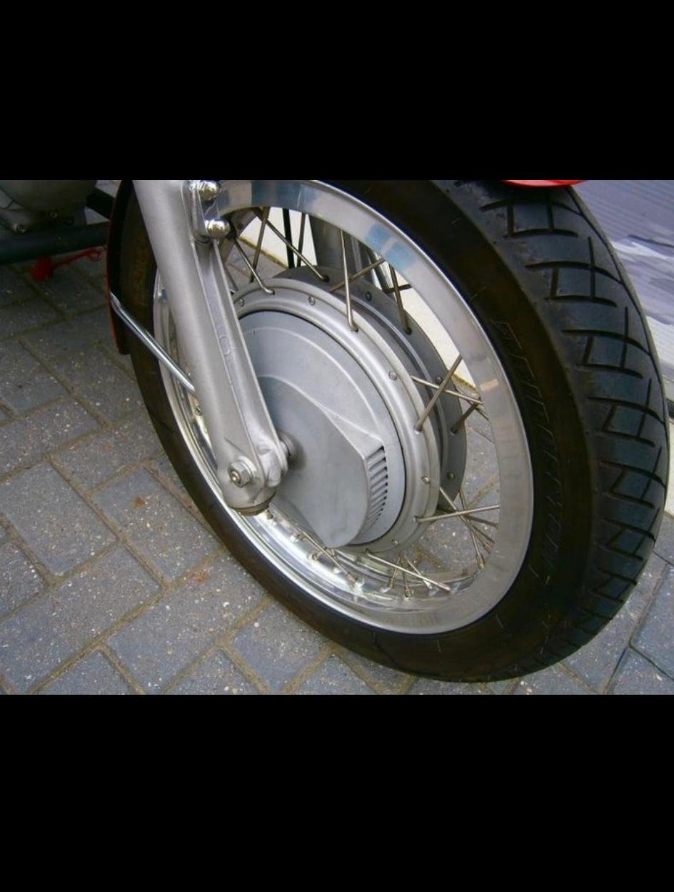 Rueda de motocicleta con neumático, disco de freno, radios y motor eléctrico en el centro.