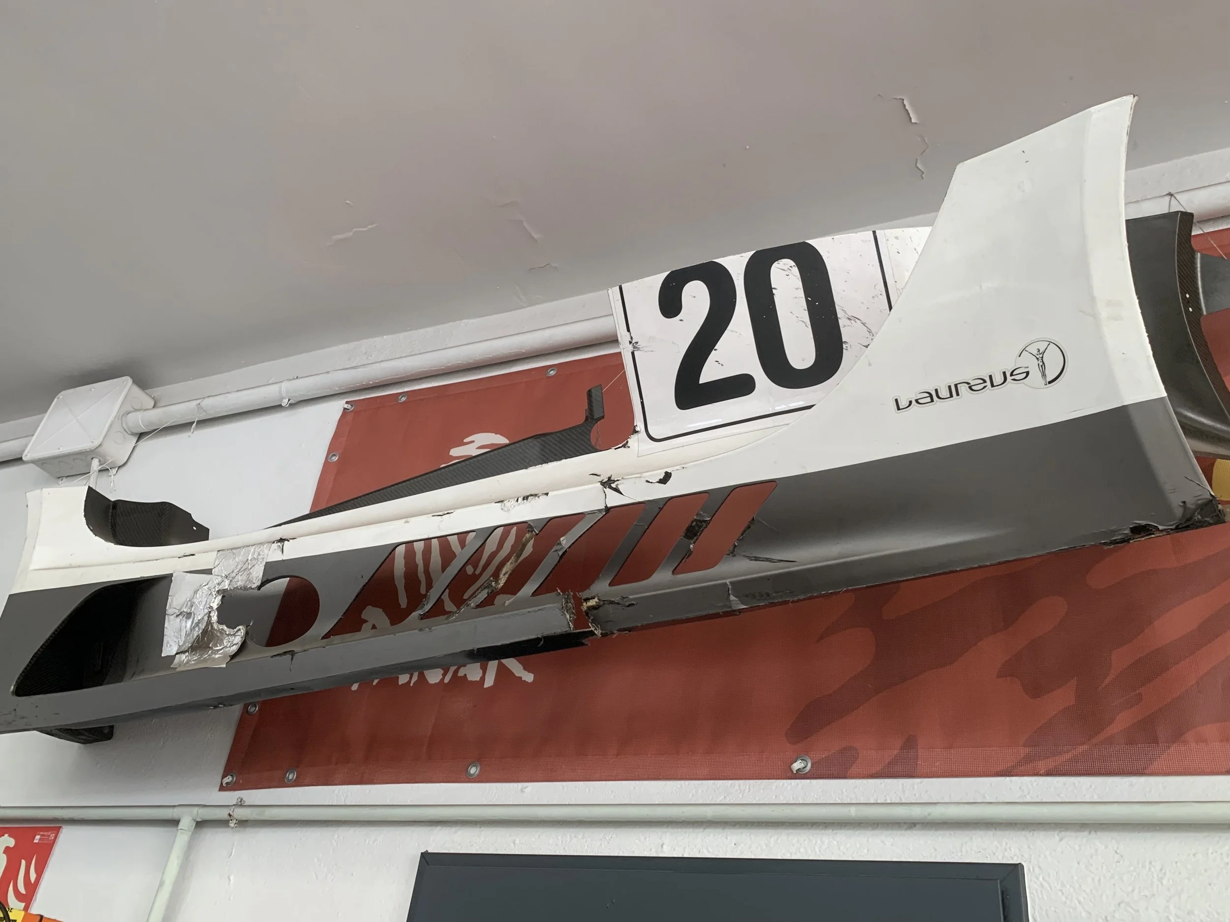 A racing car front wing with the number 20 and Laureus logo mounted on a wall.