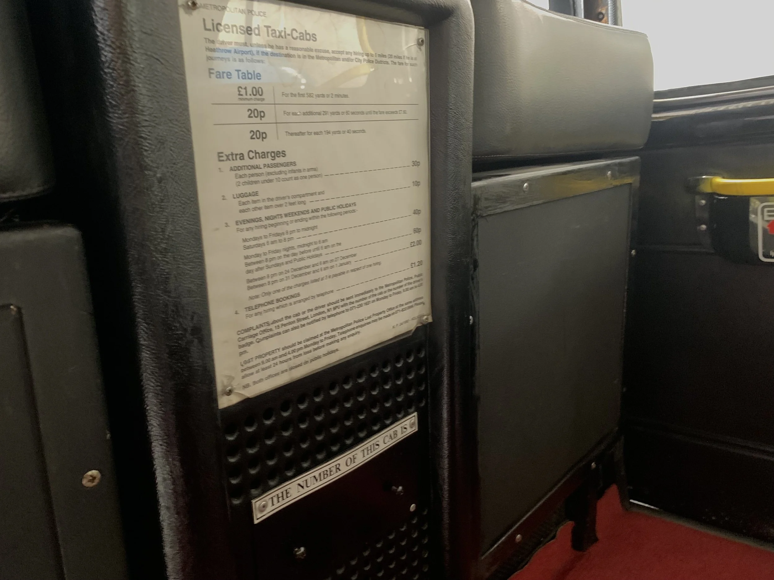 Tarifa de taxi en inglés en un panel de transporte público, detalles sobre tarifas extras y reservas por teléfono.