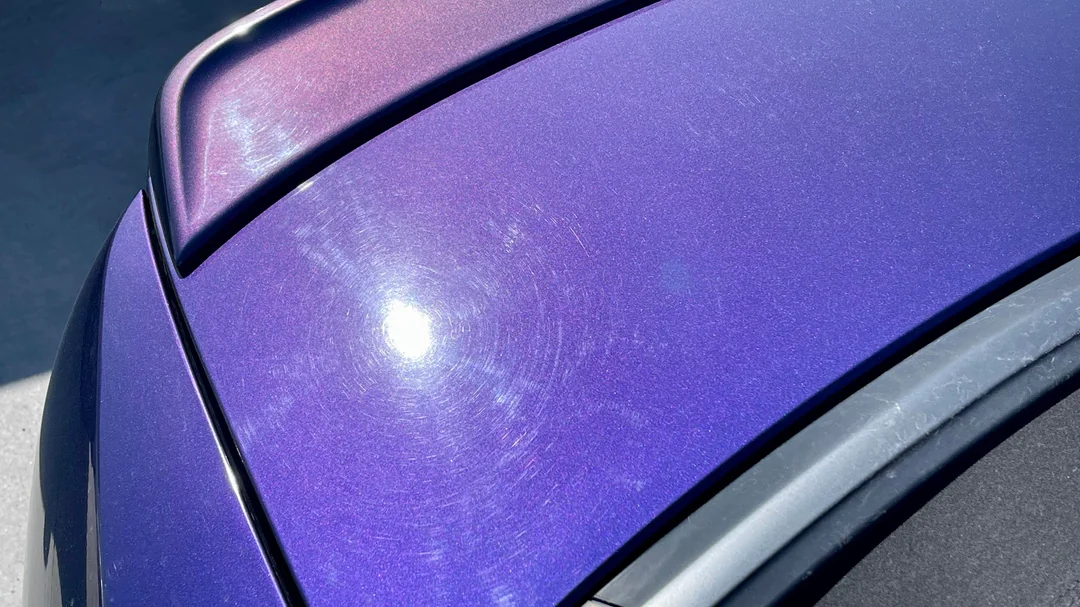 Auto de color morado con marcas de arañazos en la superficie