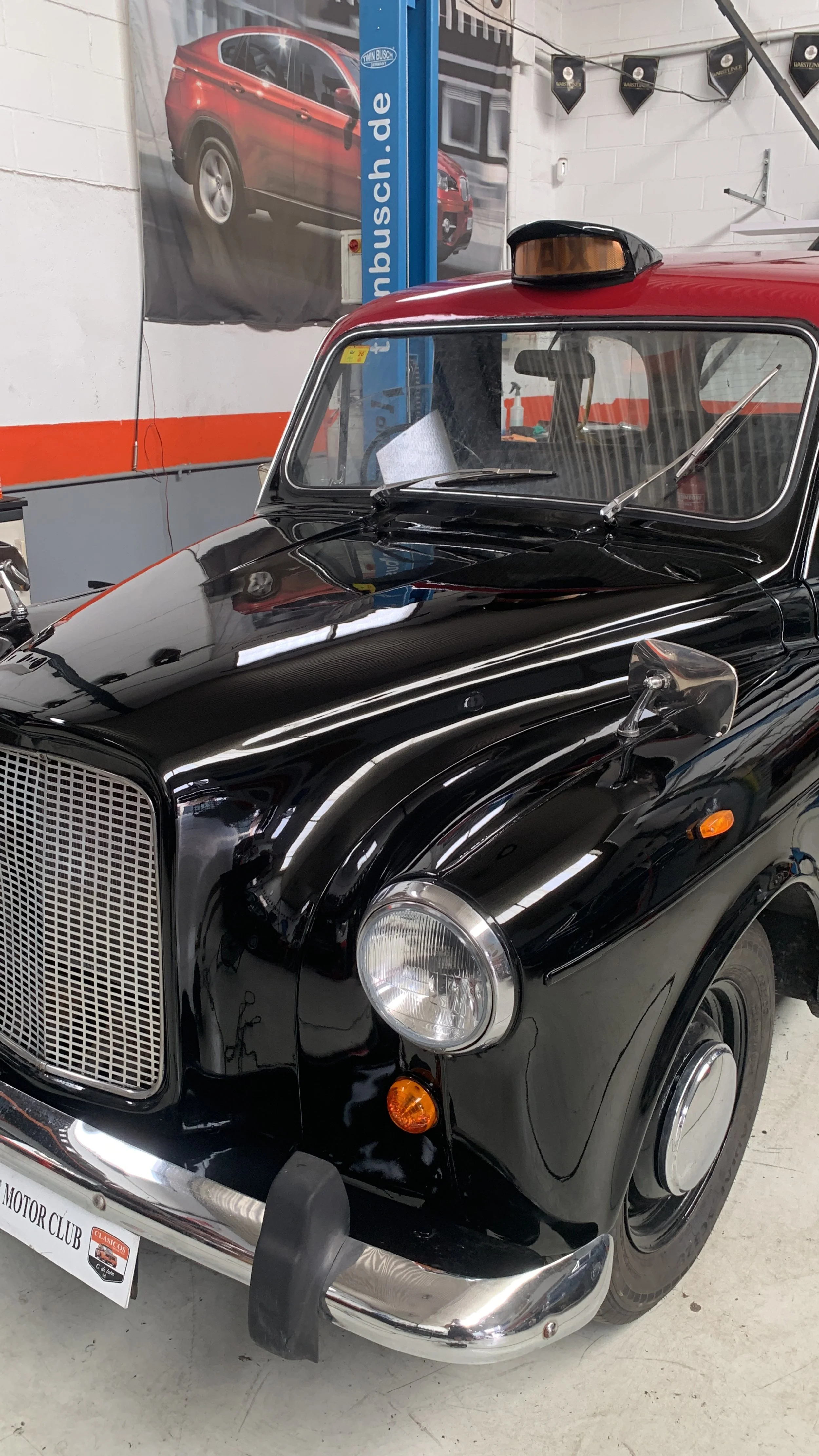 Coche clásico negro con detalles en cromo en un taller de autos.