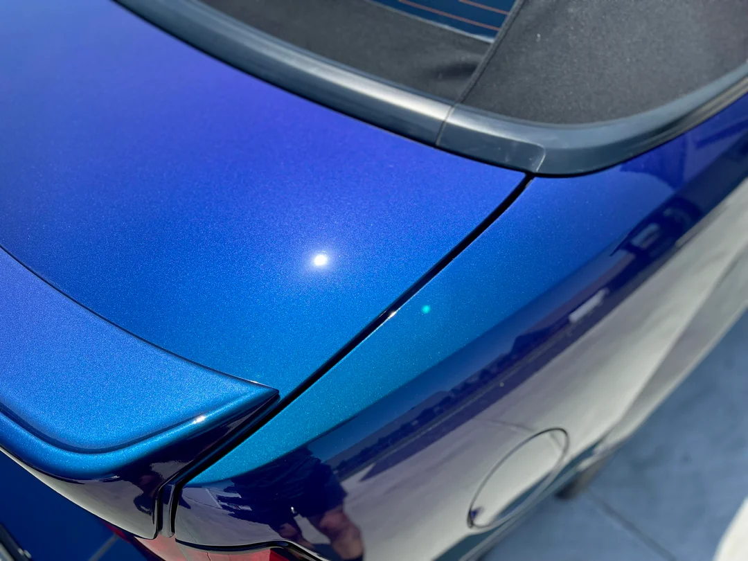 Parte trasera de un coche azul con acabado metálico