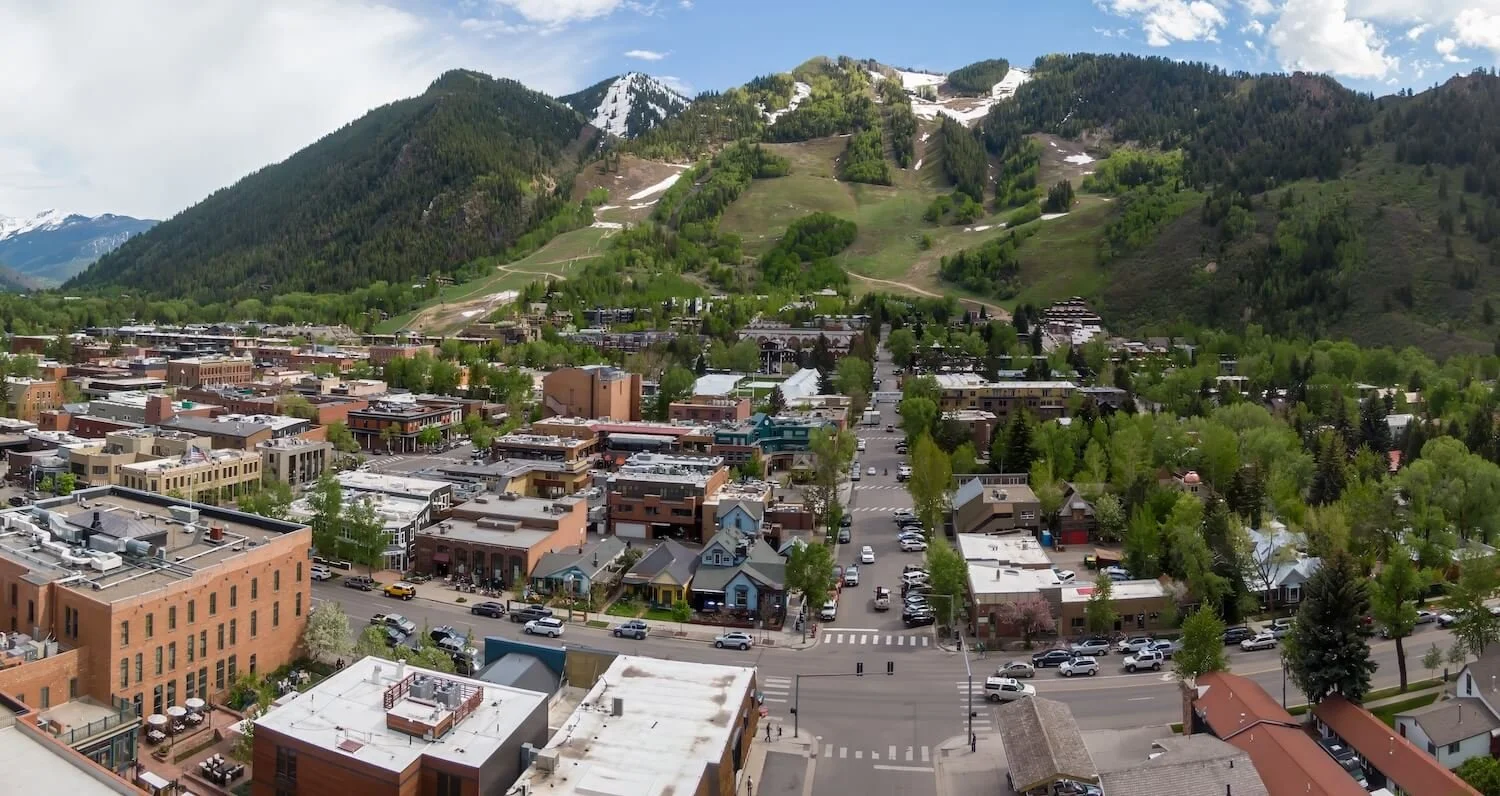 Panoramic view of downtown Aspen with shops and restaurants at the base of green ski mountains