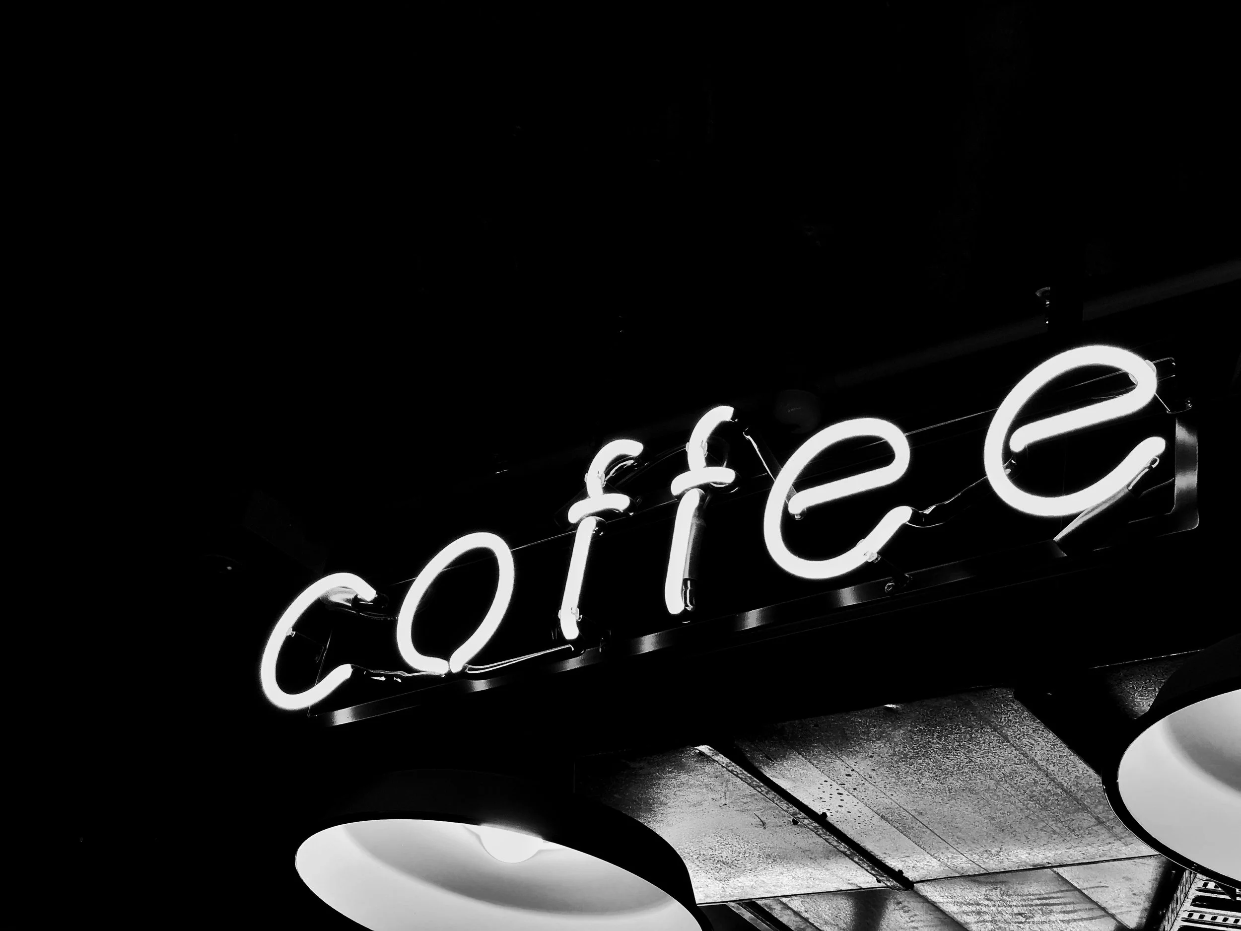 Black and white neon sign spelling 'coffee' hanging on a wall.