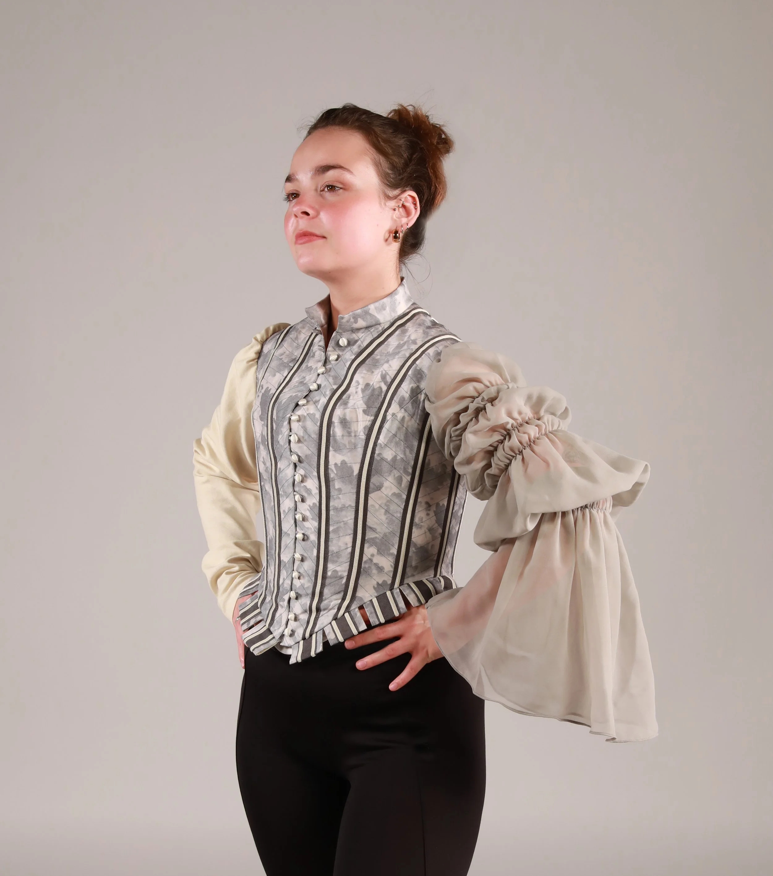 The doublet is made of silk, digitally printed with a custom oak leak design. it is adorned with velvet and grosgrain ribbon layered to created a striped effect. One sleeve is made with cotton sateen and the other chiffon, both hand dyed to match sha