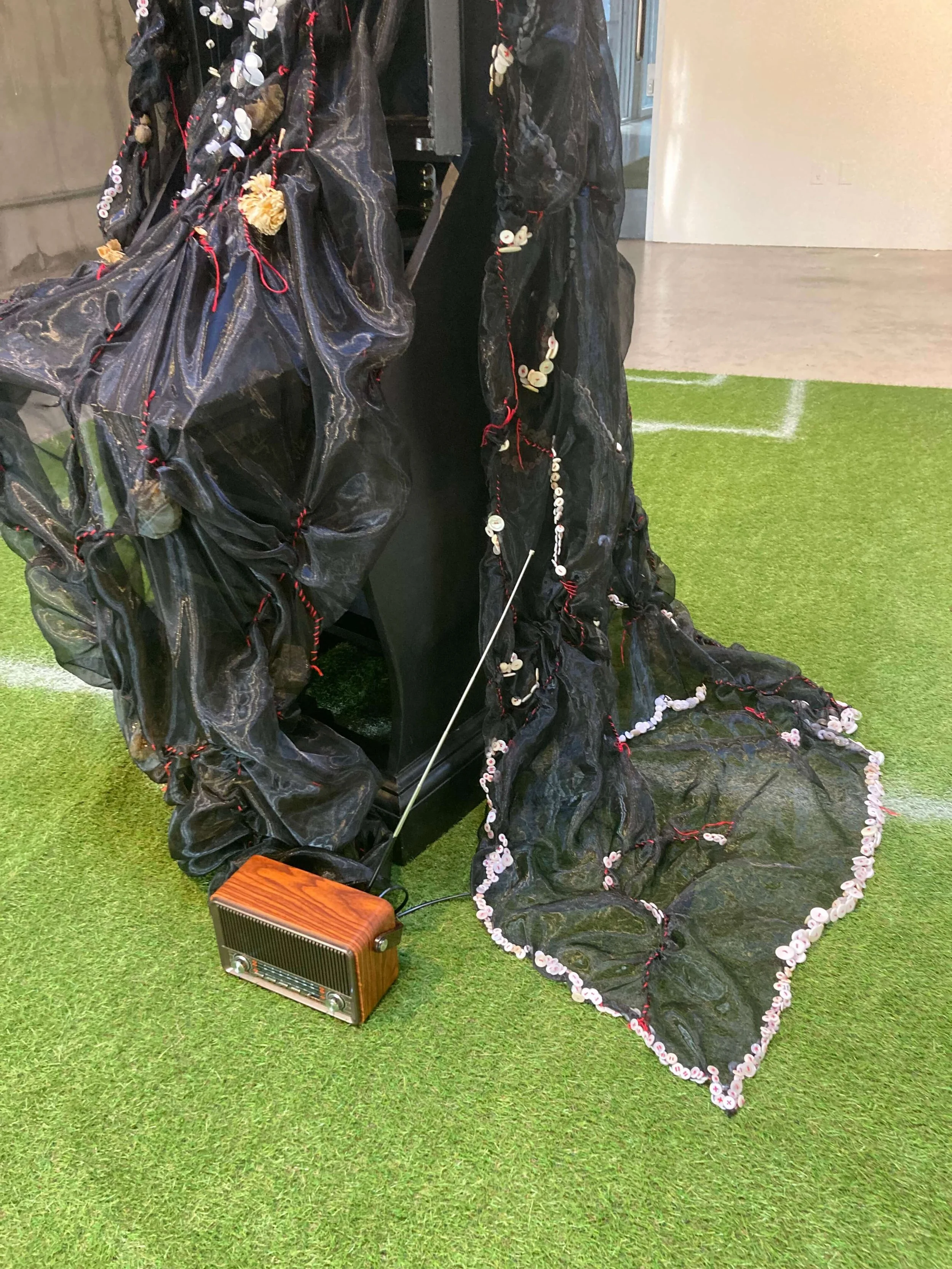   Yue Xiang    Witness,  2025  10’ x 16’ x 6’3  Broken china, Buttons, Chiffon,  Dried flowers, Embroidery thread,  hand labor, Palestine vs Hong Kong 2023 Asia Cup Group C game comments, Radio speaker,  Refurbished cabinet, Recorded artist breathing