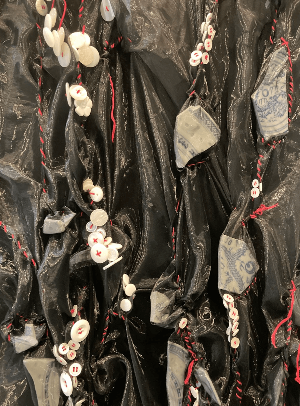   Yue Xiang    Witness,  2025  10’ x 16’ x 6’3  Broken china, Buttons, Chiffon,  Dried flowers, Embroidery thread,  hand labor, Palestine vs Hong Kong 2023 Asia Cup Group C game comments, Radio speaker,  Refurbished cabinet, Recorded artist breathing