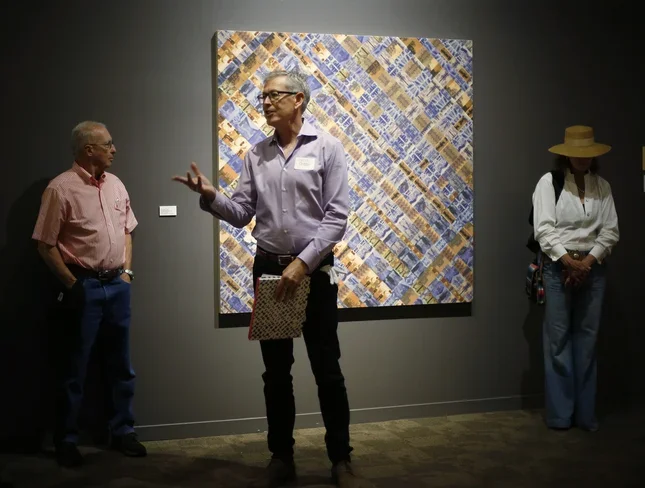 Guest Curater Roderick Kiracofe talks to exhibit guests during the opening reception at the "Found/Made" exhibition at the San Jose Museum of Quilts &amp; Textiles