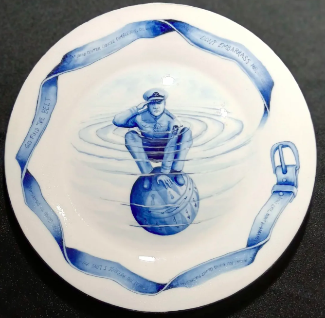 A Naval officer squats atop a sphere and salutes on a hand painted plate