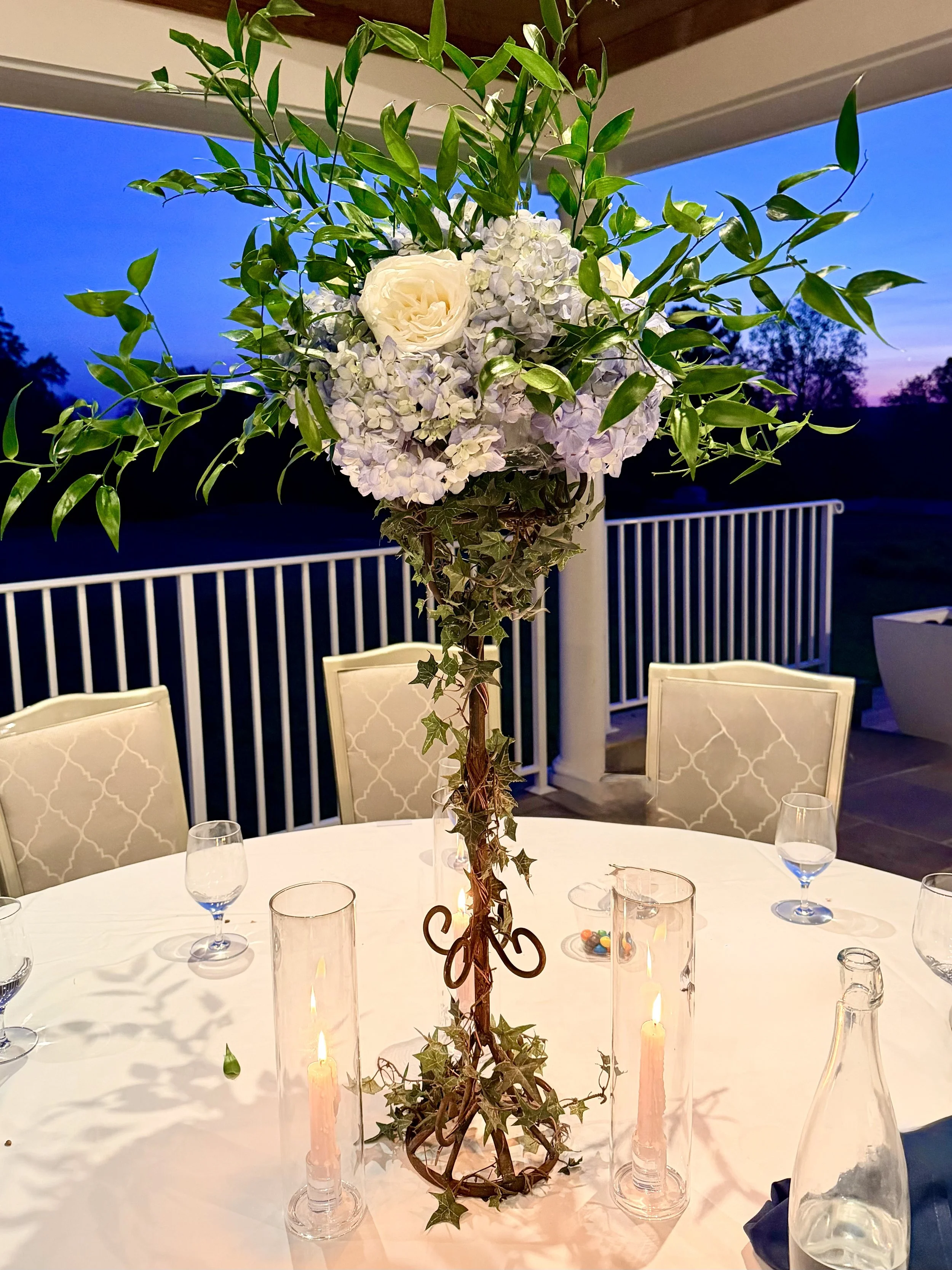 Elegant wedding tablescape featuring sculptural floral arrangements and glowing hurricane candles