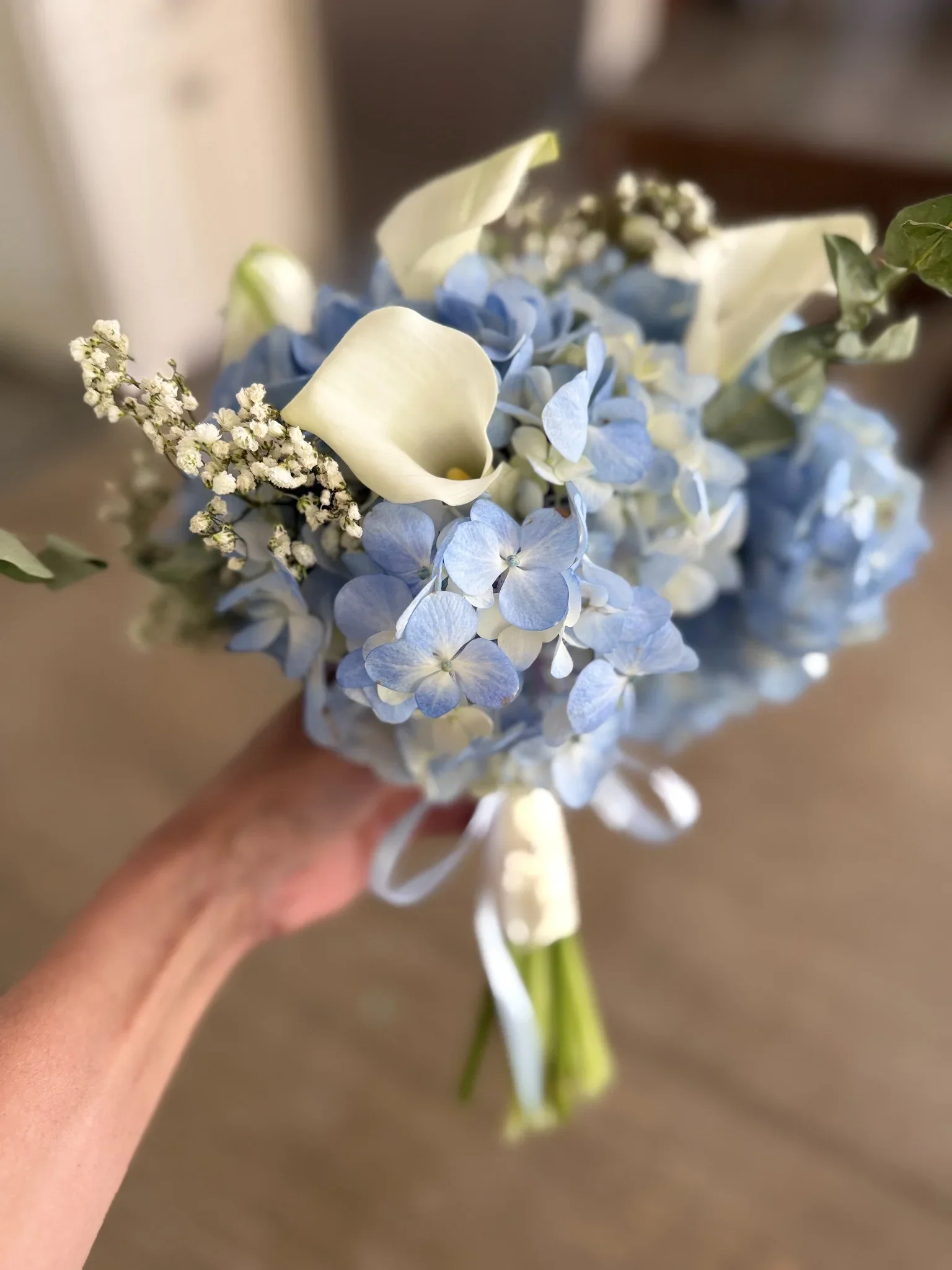 A bouquet of blue and white flowers being held by a person.