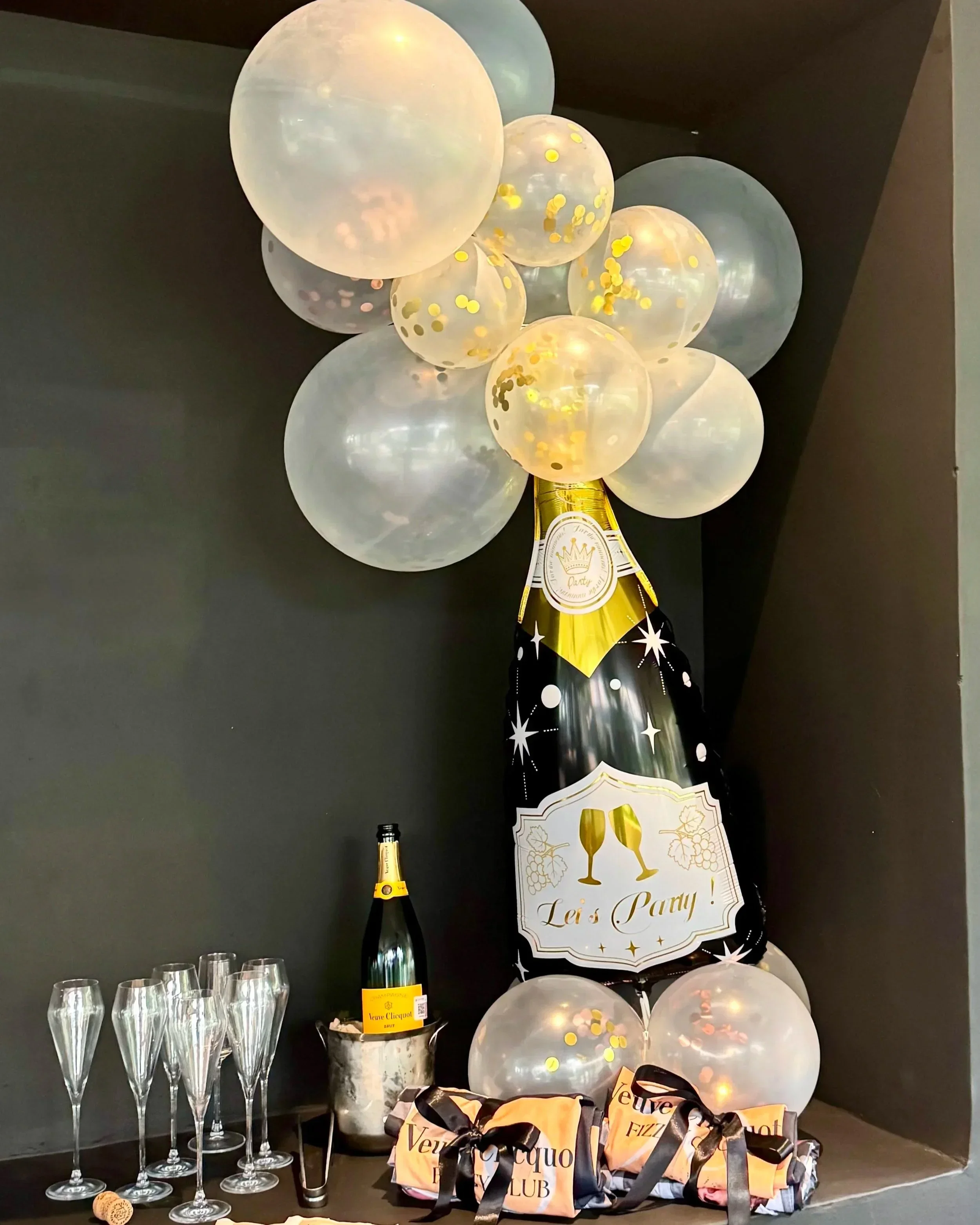 Balloons, champagne bottle, glasses, and party favors for a celebration, with a 