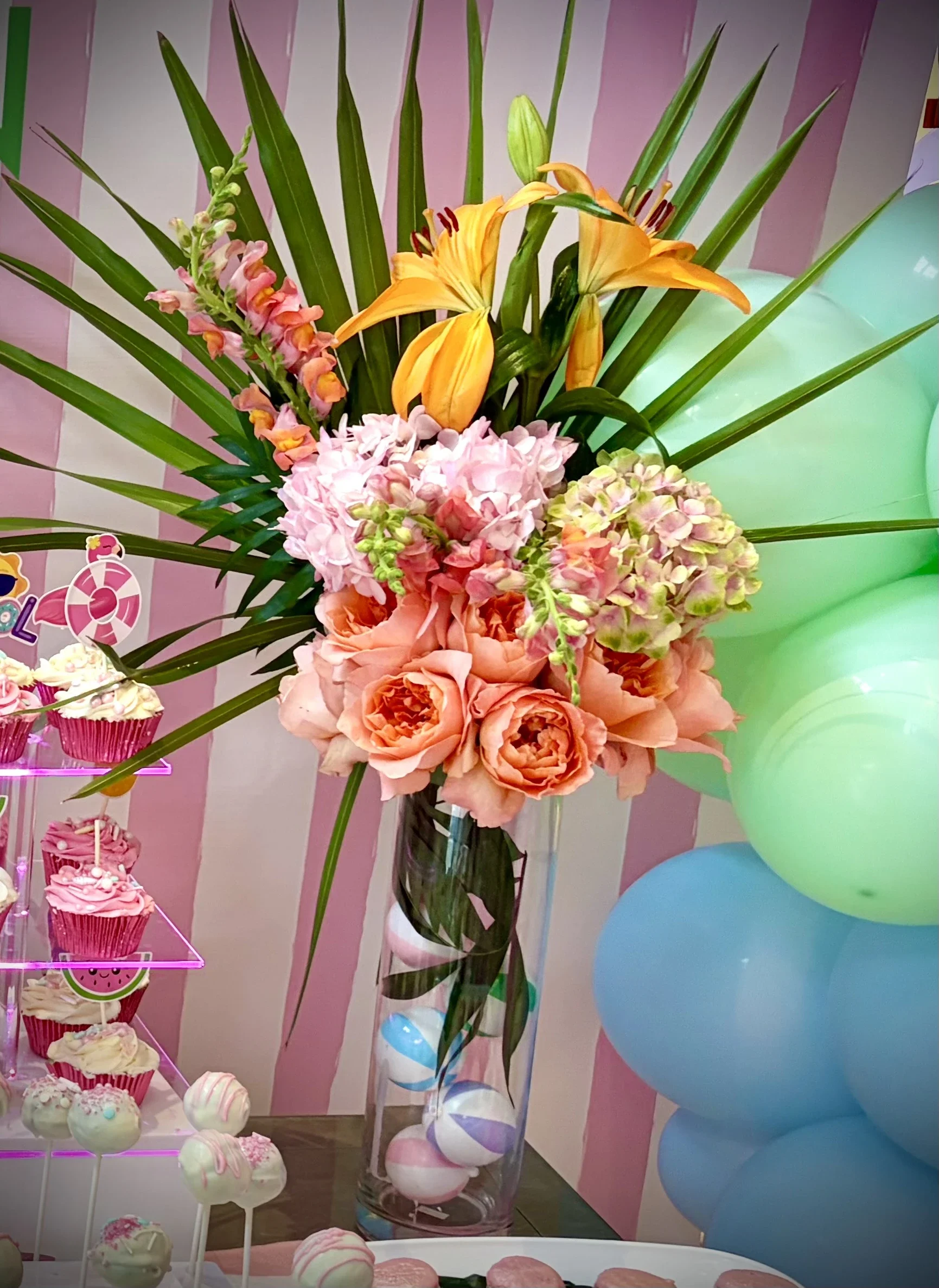Luxury tropical floral centerpiece featuring peach garden roses, hydrangeas, lilies, and palm leaves for an upscale birthday celebration in New Jersey by Stellar View Events.