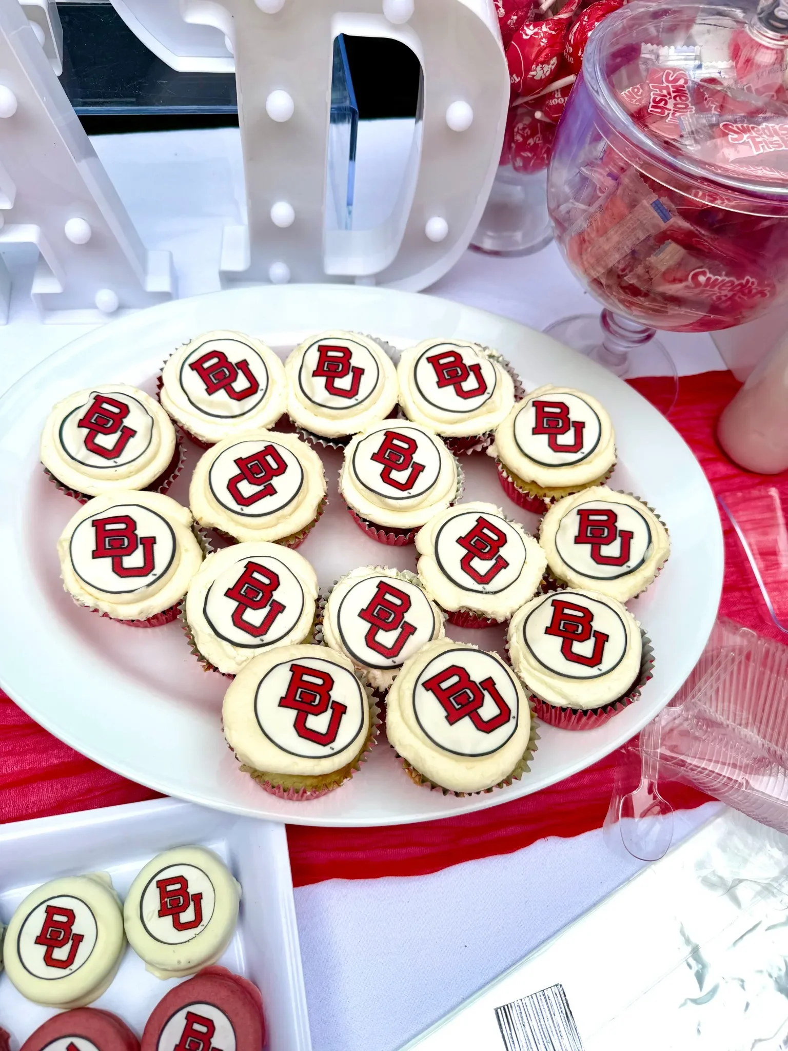 Cupcakes decorated with the logo of Boston University, arranged on a white platter for a graduation party in NJ.