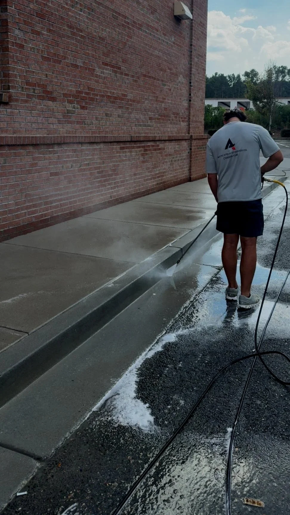 Professional pressure washer washing the sidewalk outside a brick fast food building