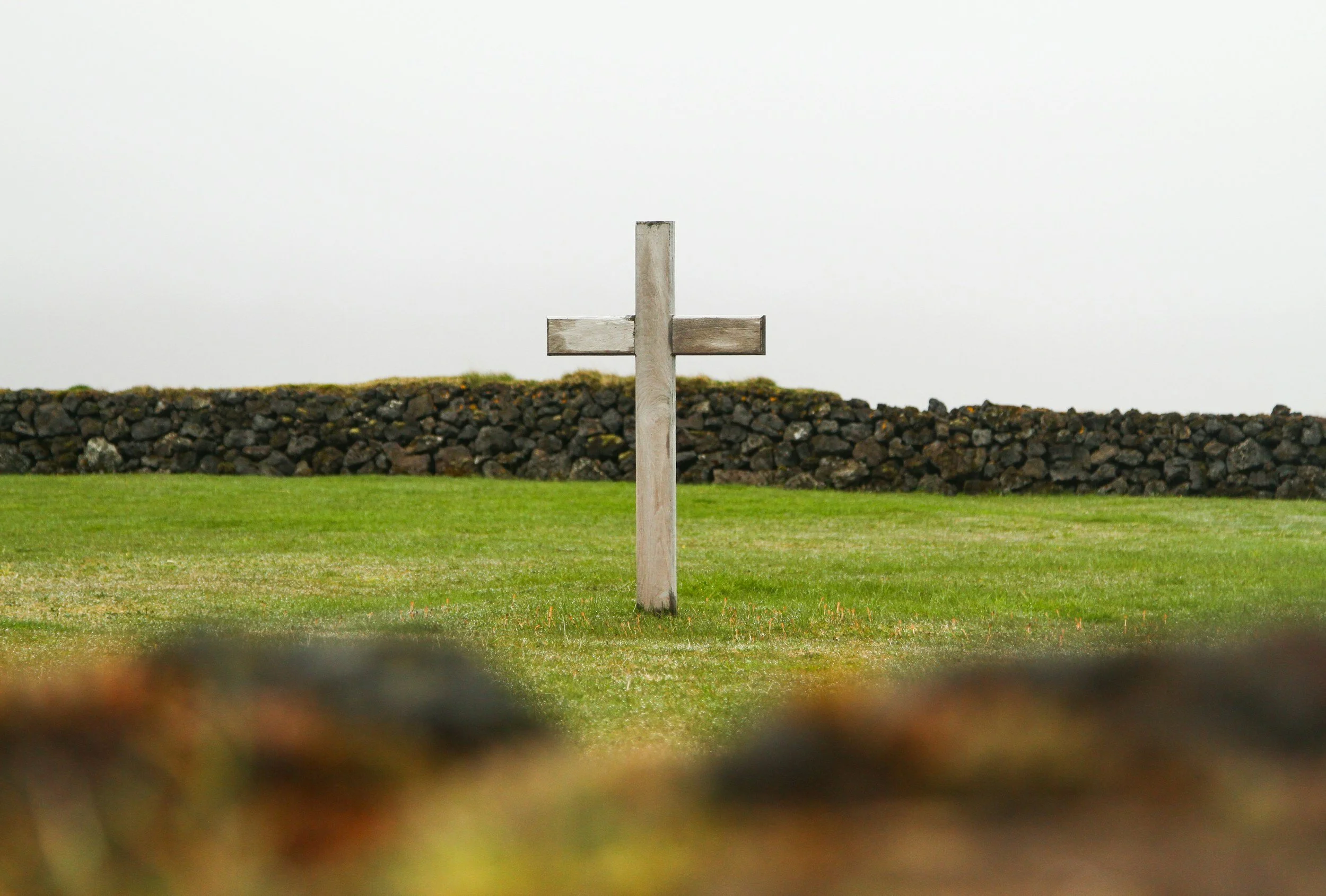 Wooden cross standing in an open field, symbolizing Christian faith, hope, and comfort during grief and loss.