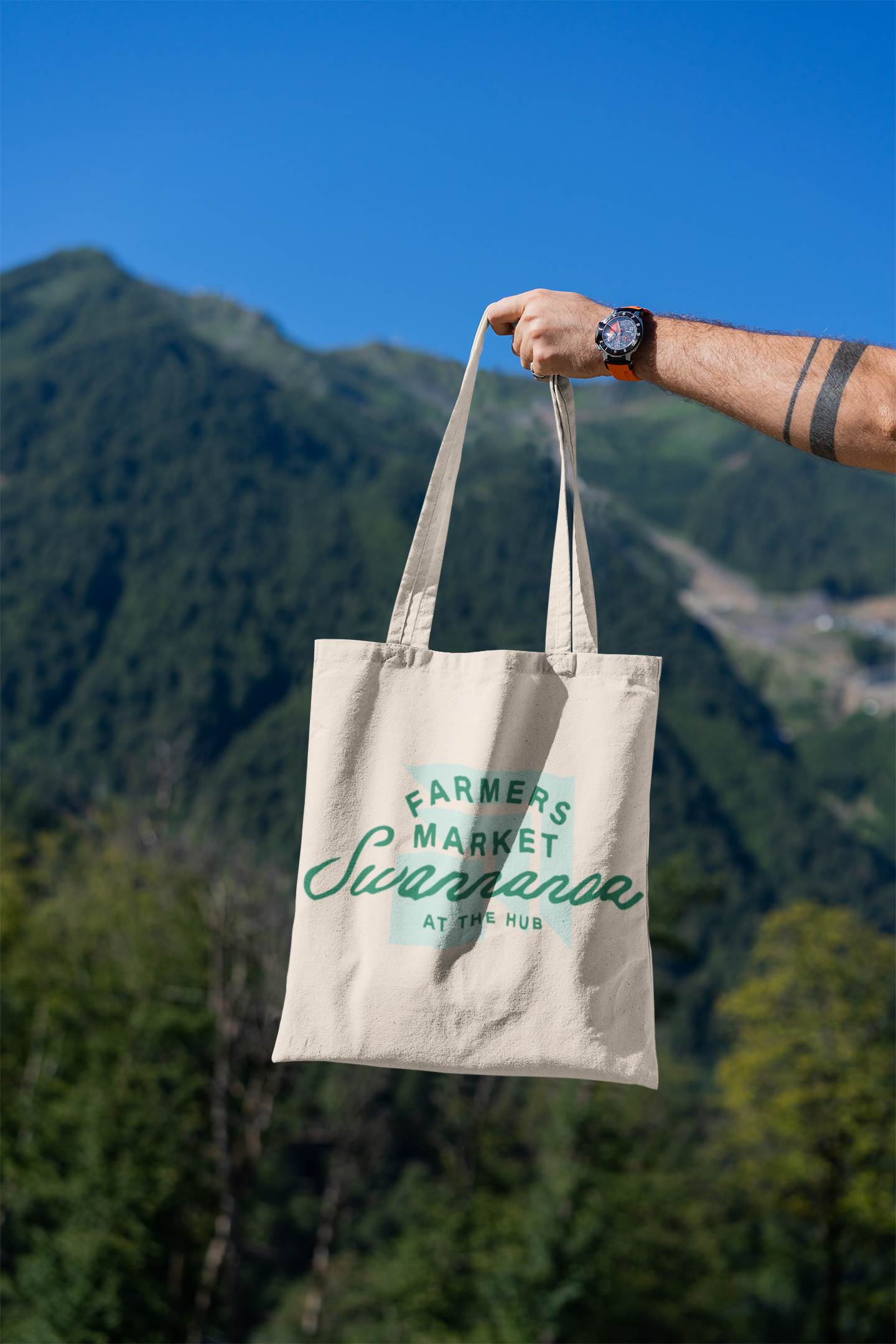 mockup-featuring-a-man-s-hand-holding-a-tote-bag-against-a-natural-scenery-3131-el1.png
