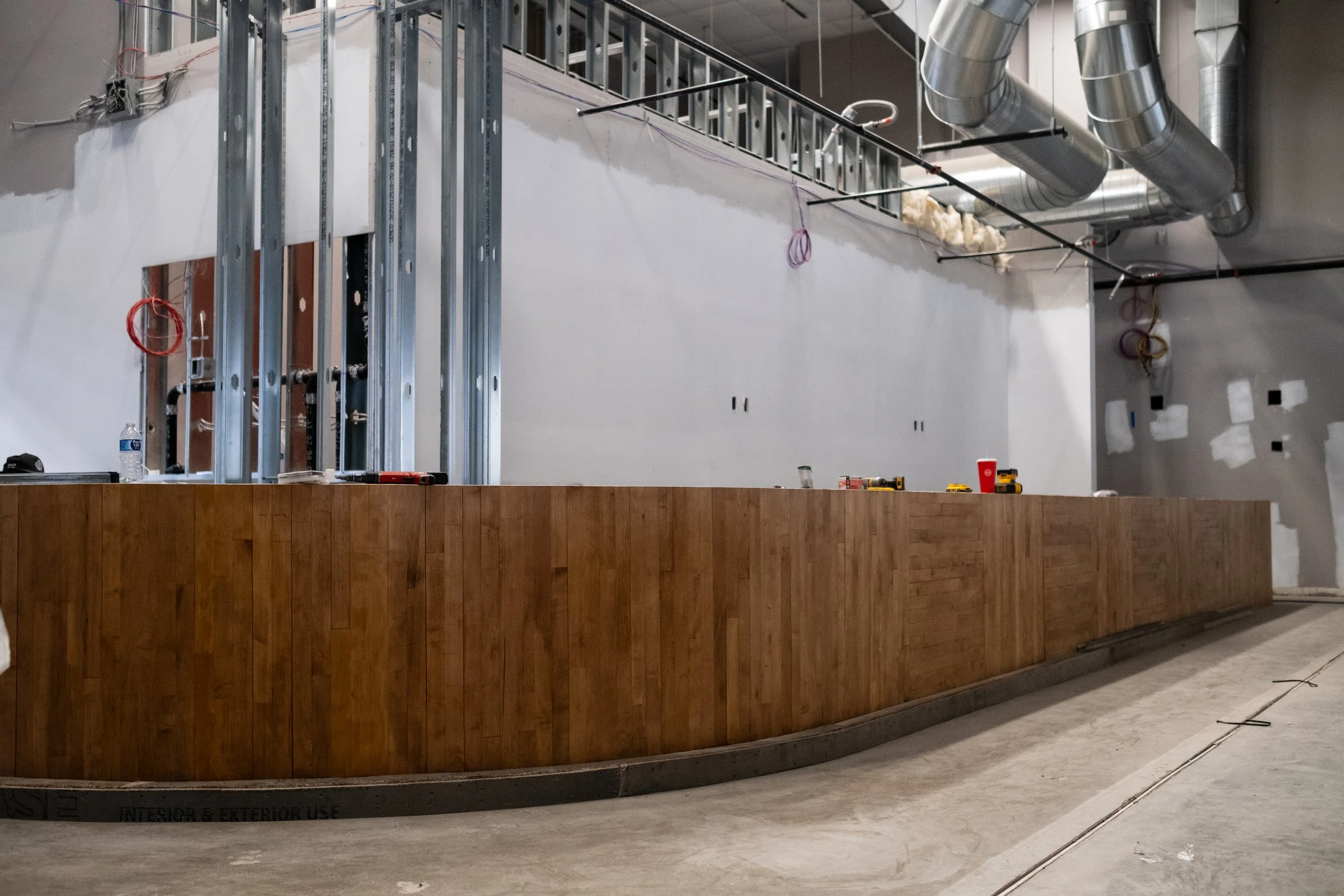 Construction site with a wooden counter, metal framing, exposed ductwork, and unfinished walls.