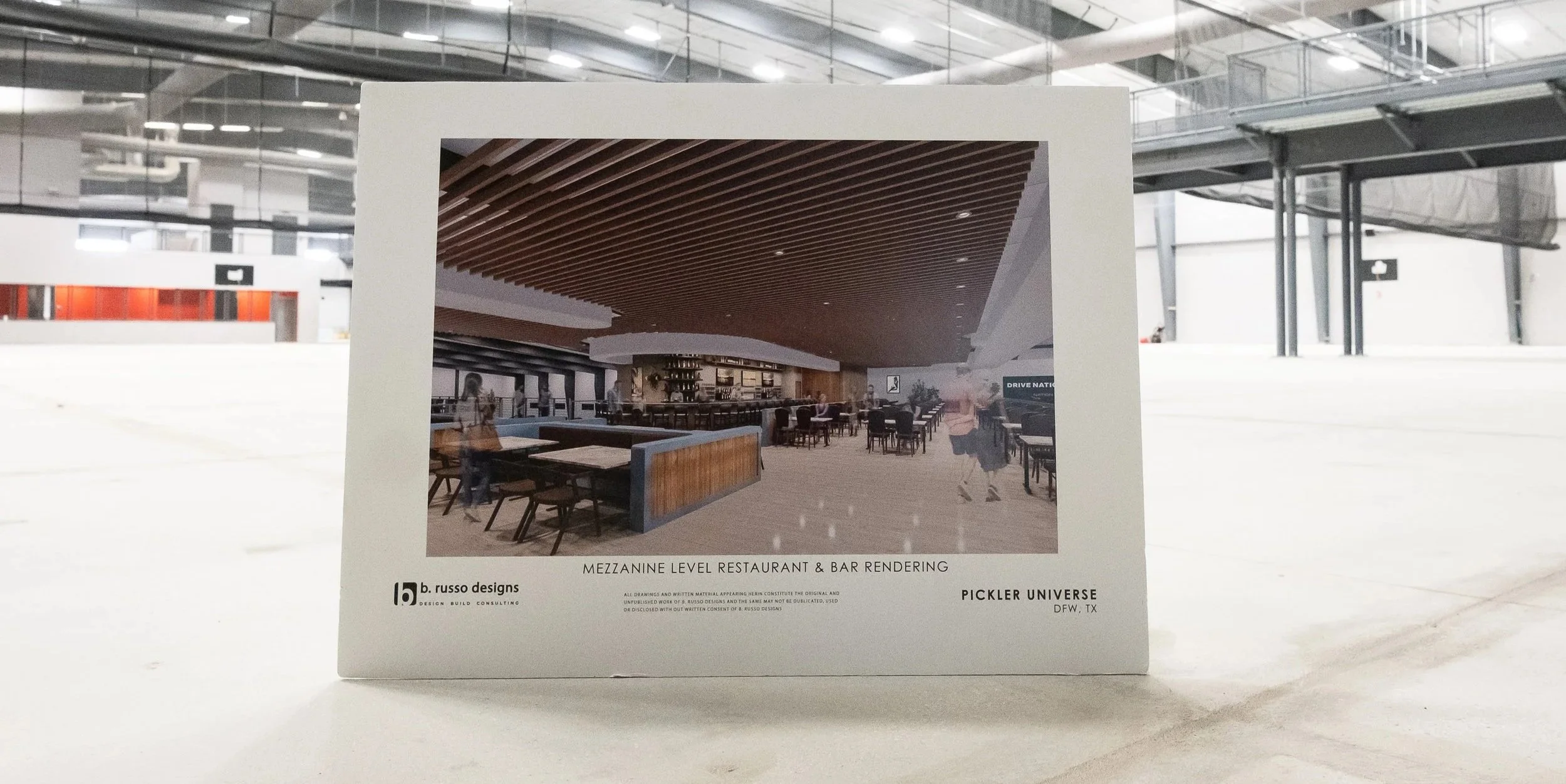 A printed rendering of a mezzanine level restaurant and bar design, showing a modern interior with wooden ceiling panels, a curved bar, and seating areas, mounted on a white display board set against a large industrial space.