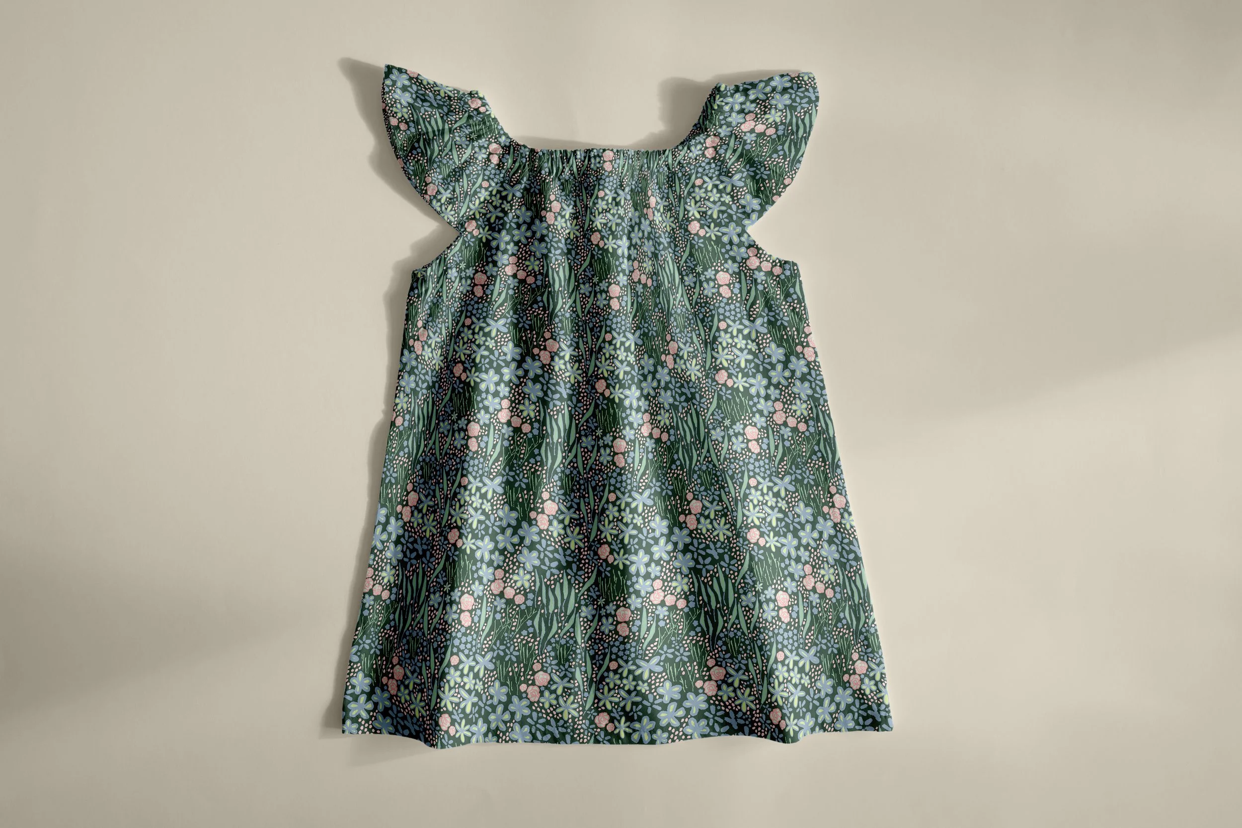 A sleeveless dress with a floral pattern featuring pink, blue, and green colors hanging against a plain background.