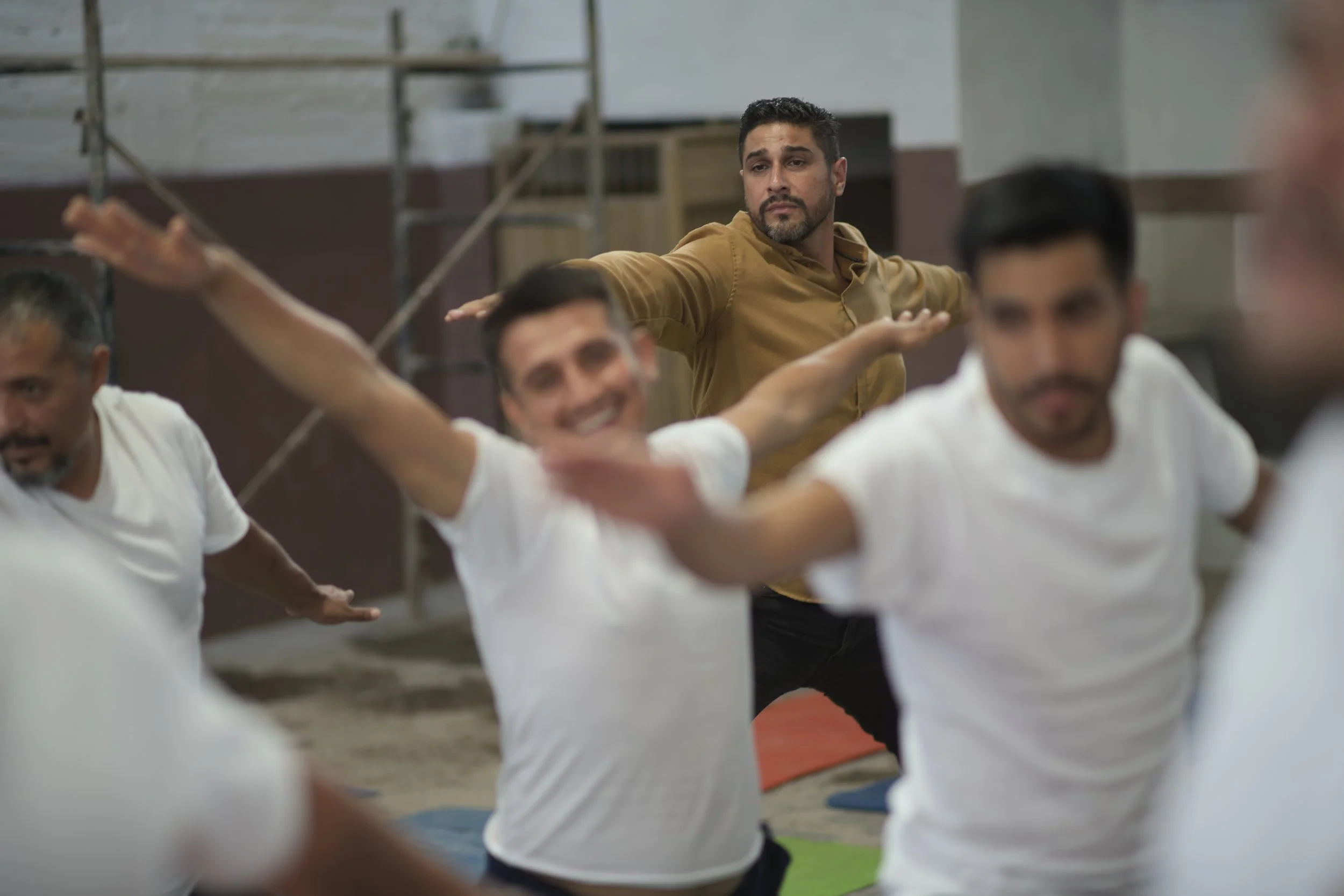 Un grupo de personas participando en una clase de yoga en una sala, haciendo yoga en equipo.