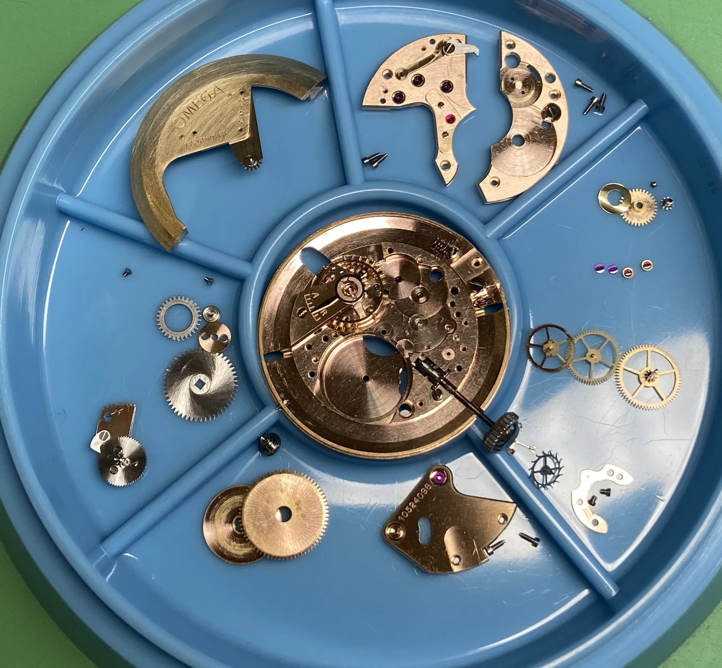 Blick auf die zerlegte Mechanik eines Uhrenwerks in einer blauen Aufbewahrungsbox.