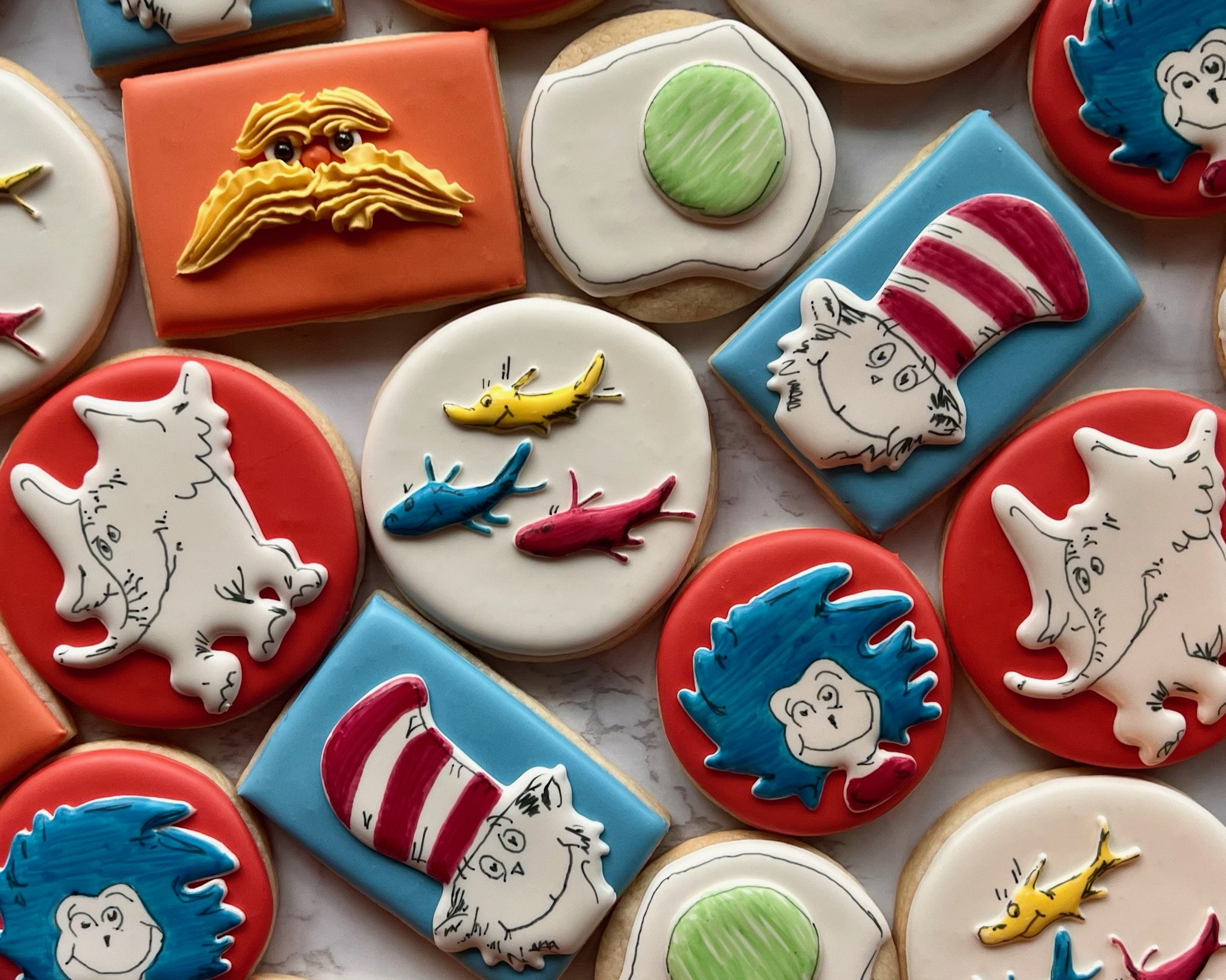 Decorated cookies featuring characters and elements from Dr. Seuss's books, including The Cat in the Hat, the Lorax, and a green egg.
