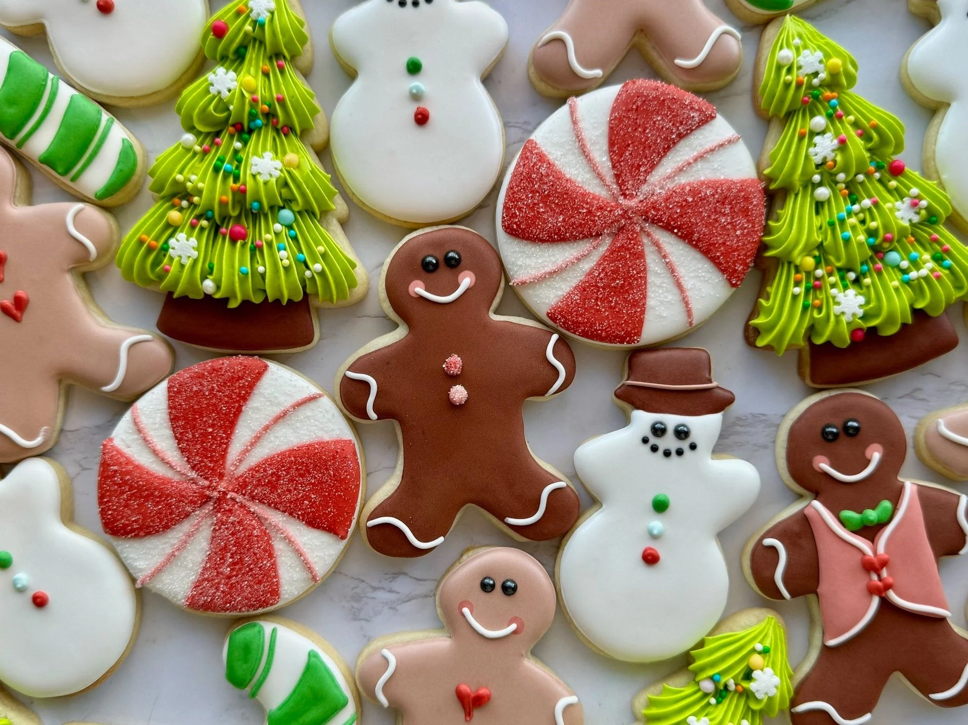 Assorted Christmas cookies including decorated gingerbread men, snowmen, Christmas trees, peppermint swirls, and candy canes.