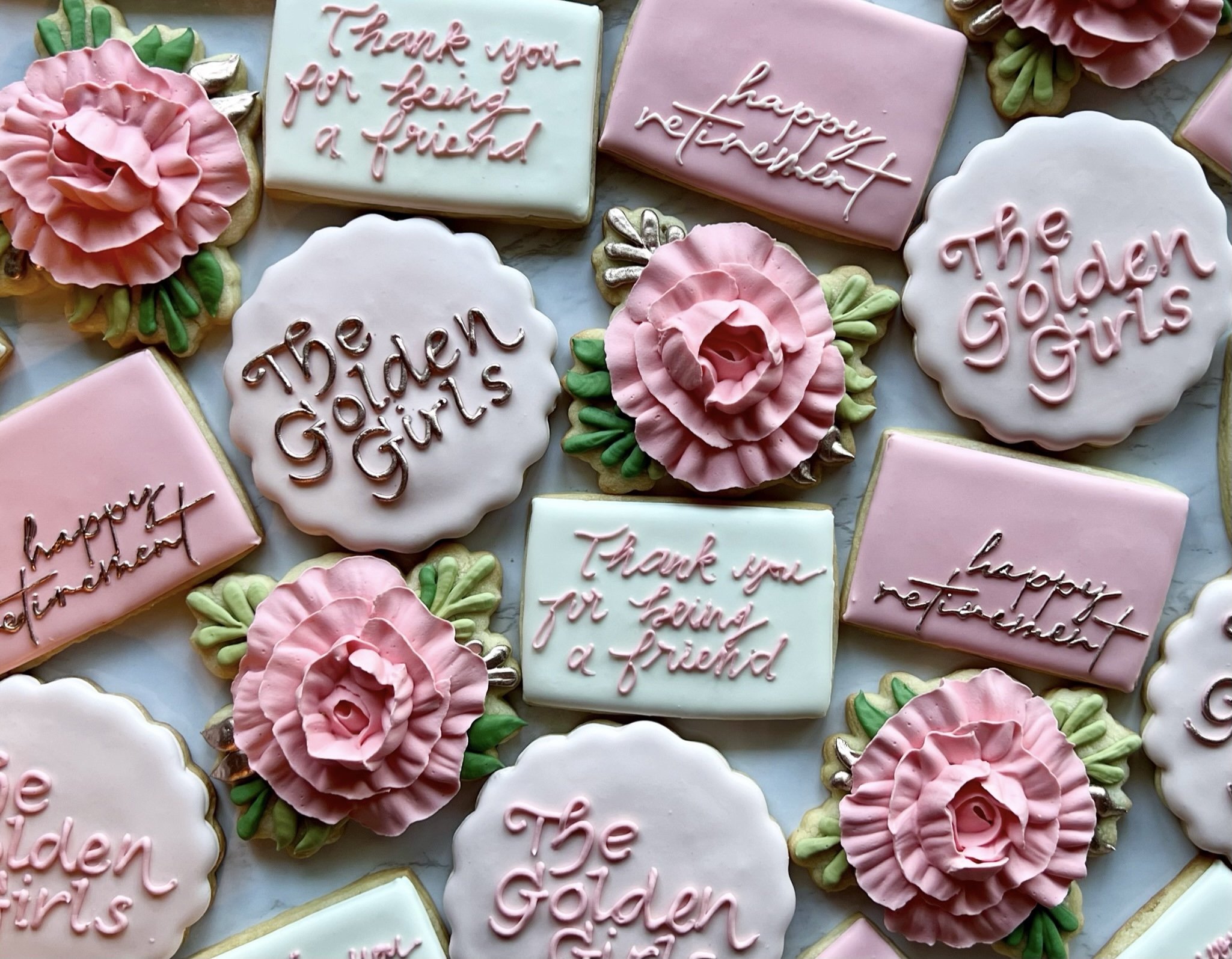 Assorted decorated cookies with messages like 'Thank you for being a friend', 'happy retirement', and 'The Golden Girls'. Cookies include pink roses and pastel-colored rectangles with icing.