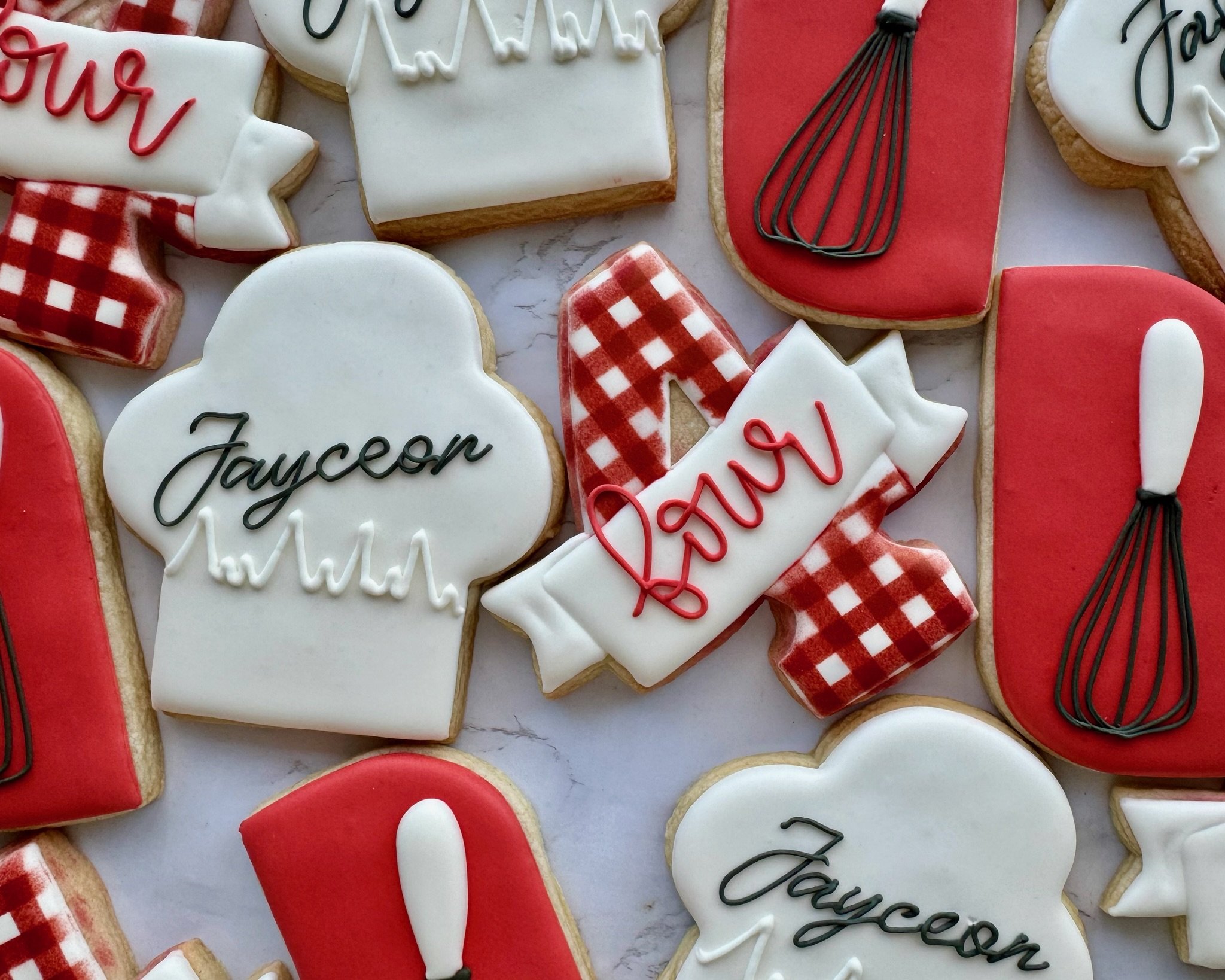 Decorated cookies with baking themes for 'Chef Fourardee' party. Includes cookies with the words 'Jayceon' and 'four', some shaped like the number four with red checkered patterns, and others resembling baking utensils with red and white icing.