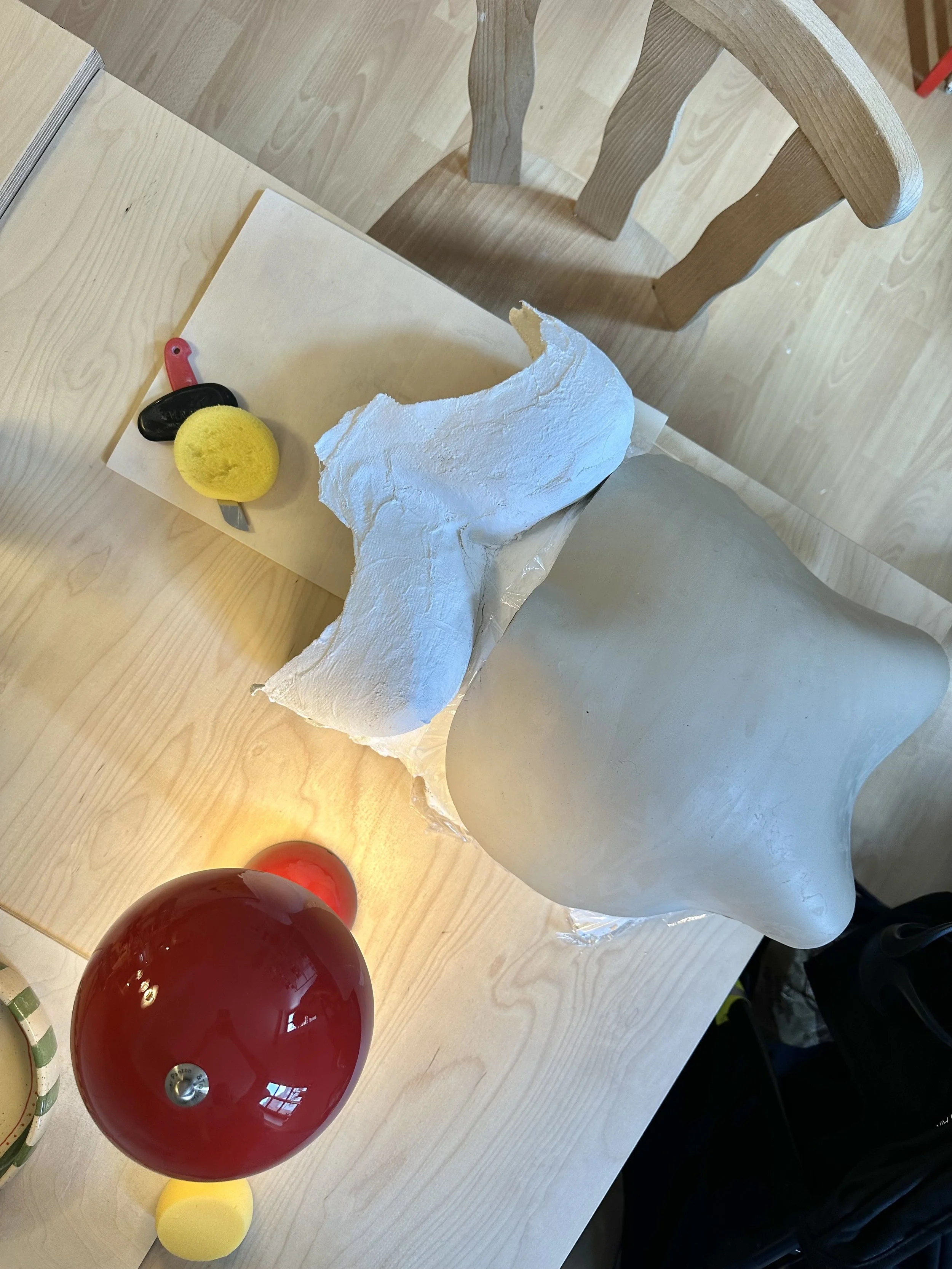 Ein Tisch mit einer Babybauchschale aus Ton und einer roten Tischlampe.