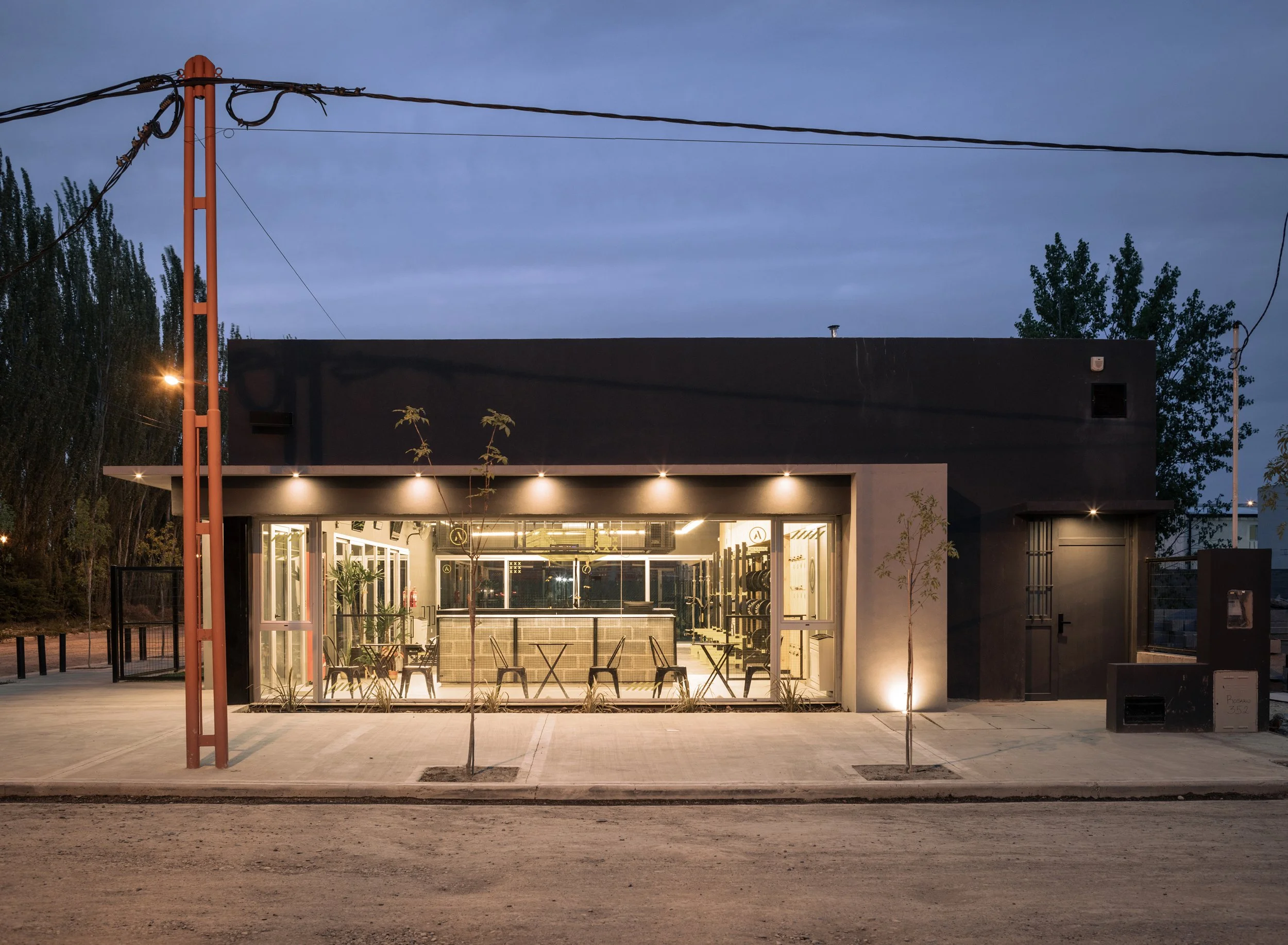 fachada de un gimnasio moderno con ventanas grandes y luces en la noche