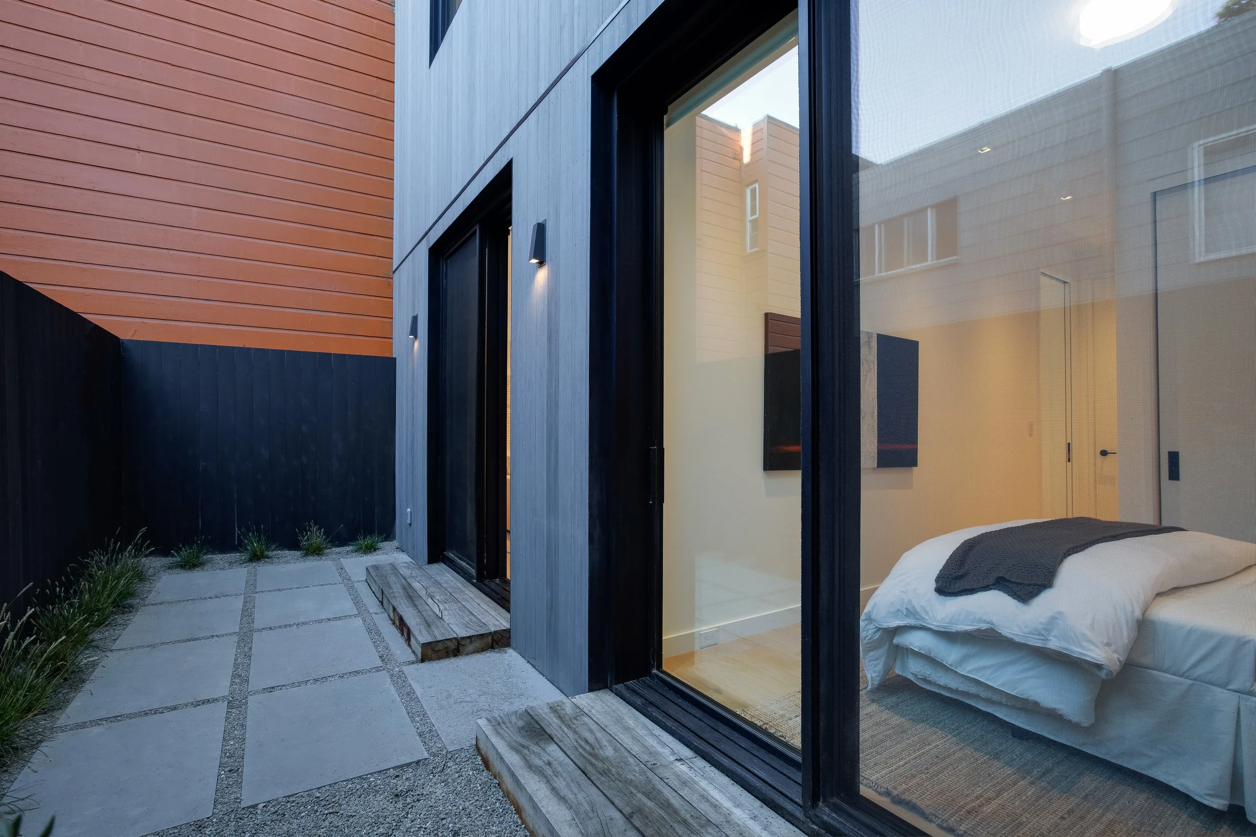 A gentle wash applied to the wooden siding, and large black sliding doors and windows give this home a soft, yet contemporary look, creating a clean coastal vibe.