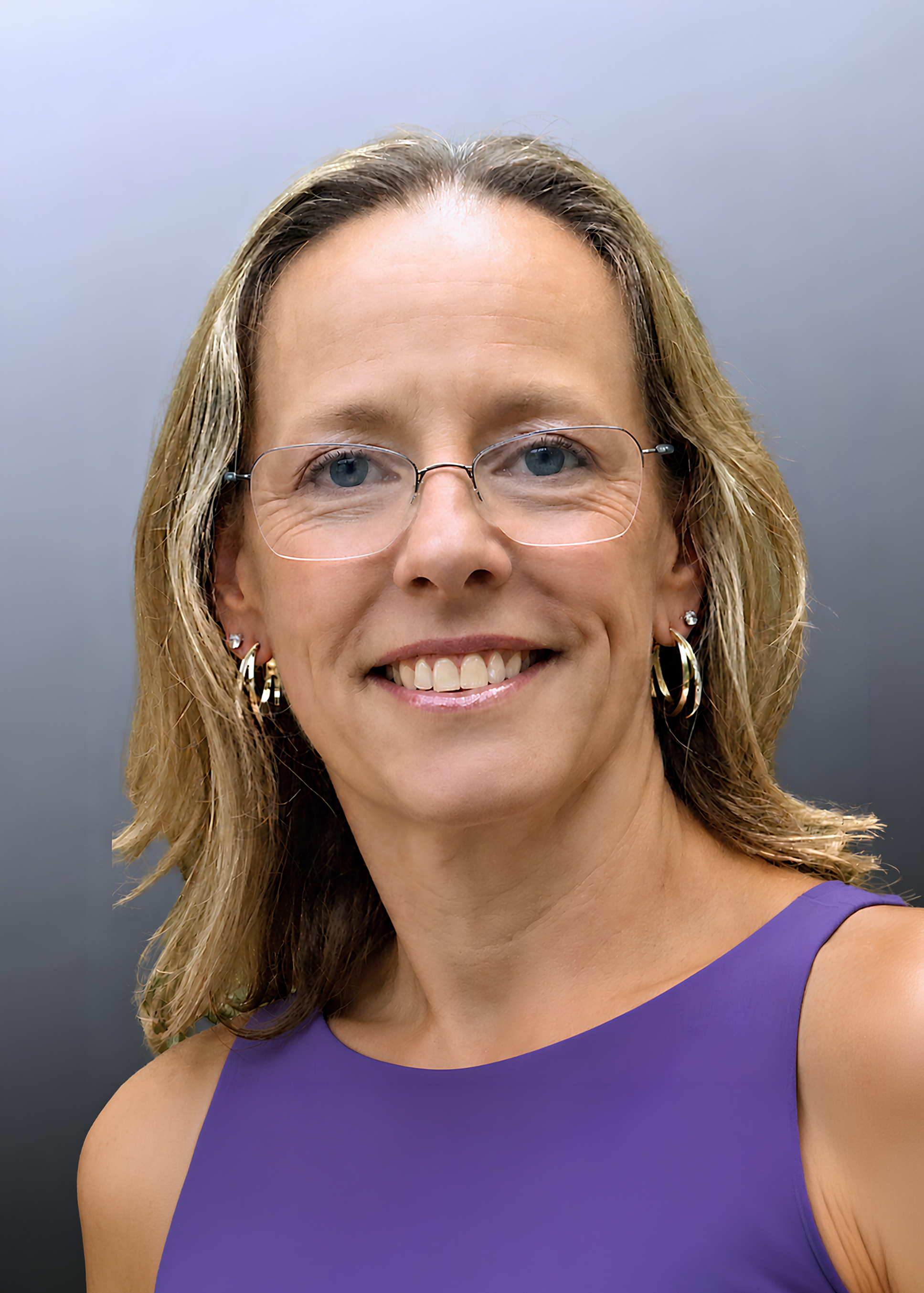 Smiling woman with glasses wearing a purple t-shirt that says 'milky moms.'