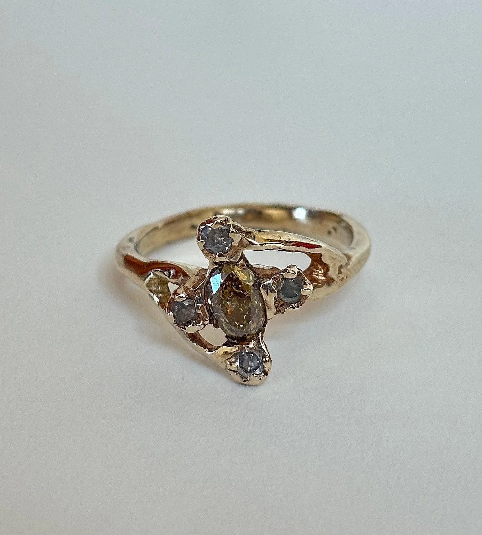 Gold ring with multiple small diamonds and light yellow gold 14k arranged in a floral pattern on a plain white background.