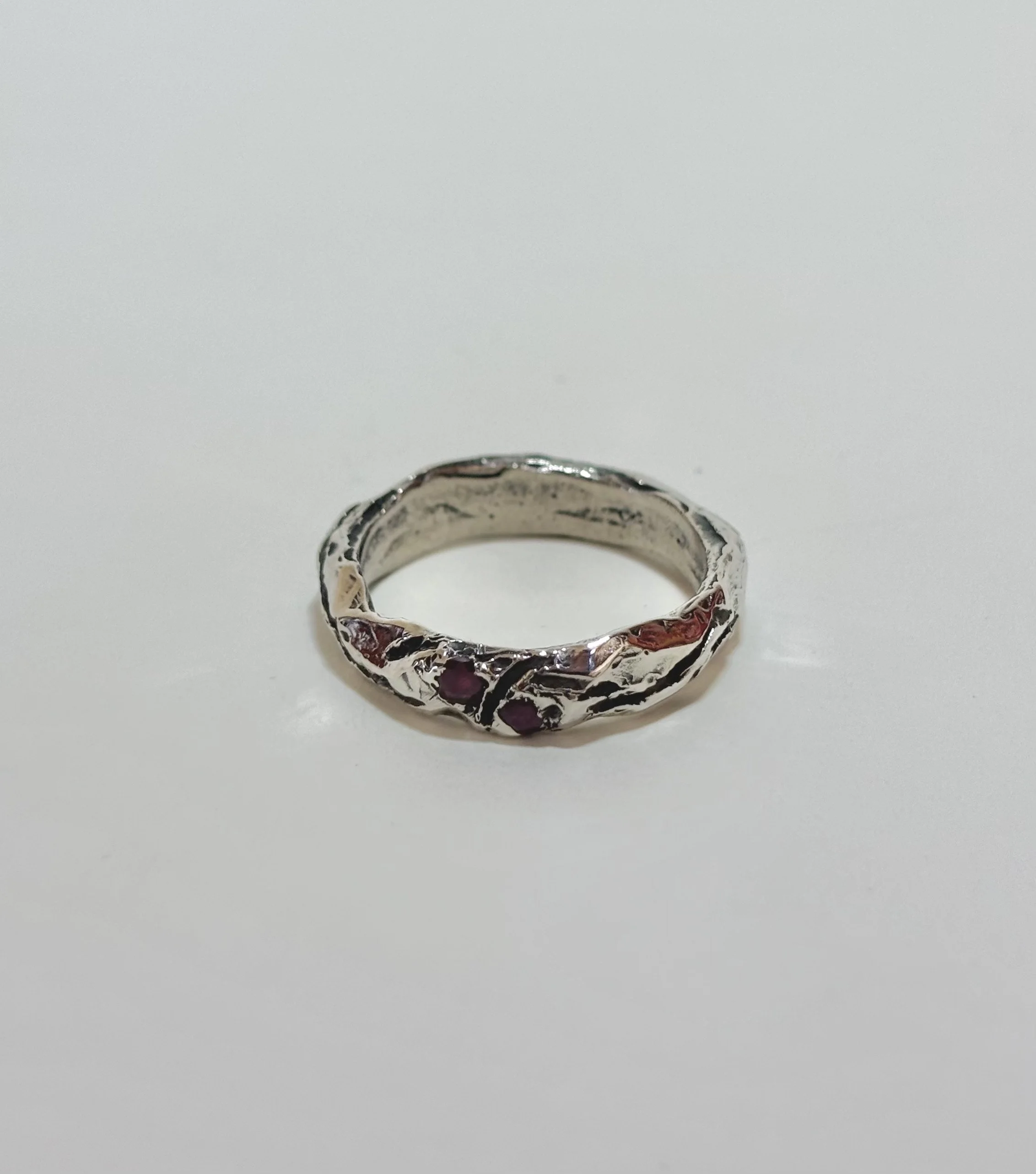Silver ring with red gemstones on a plain white background.