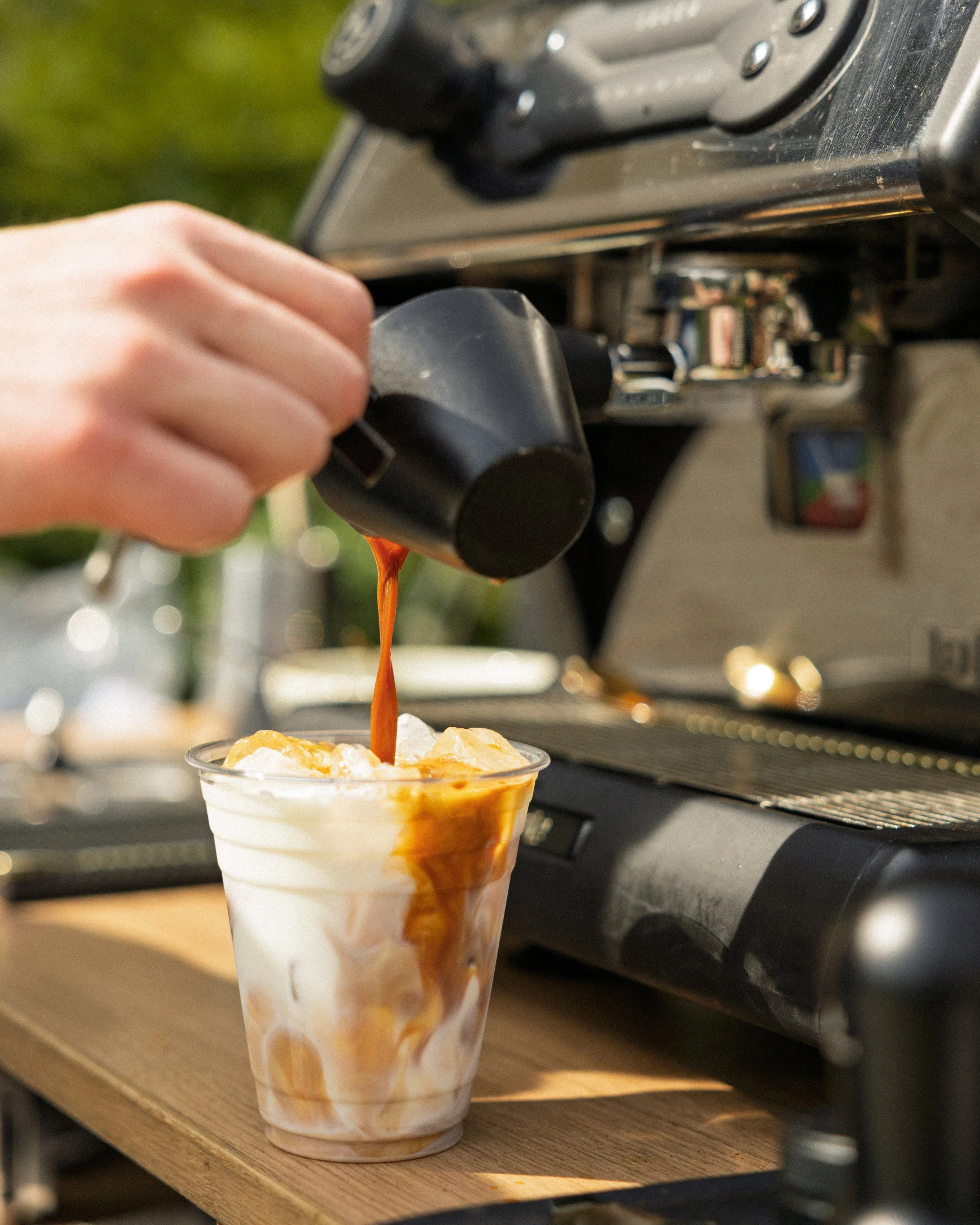 A barista pouring an espresso shot into a latte