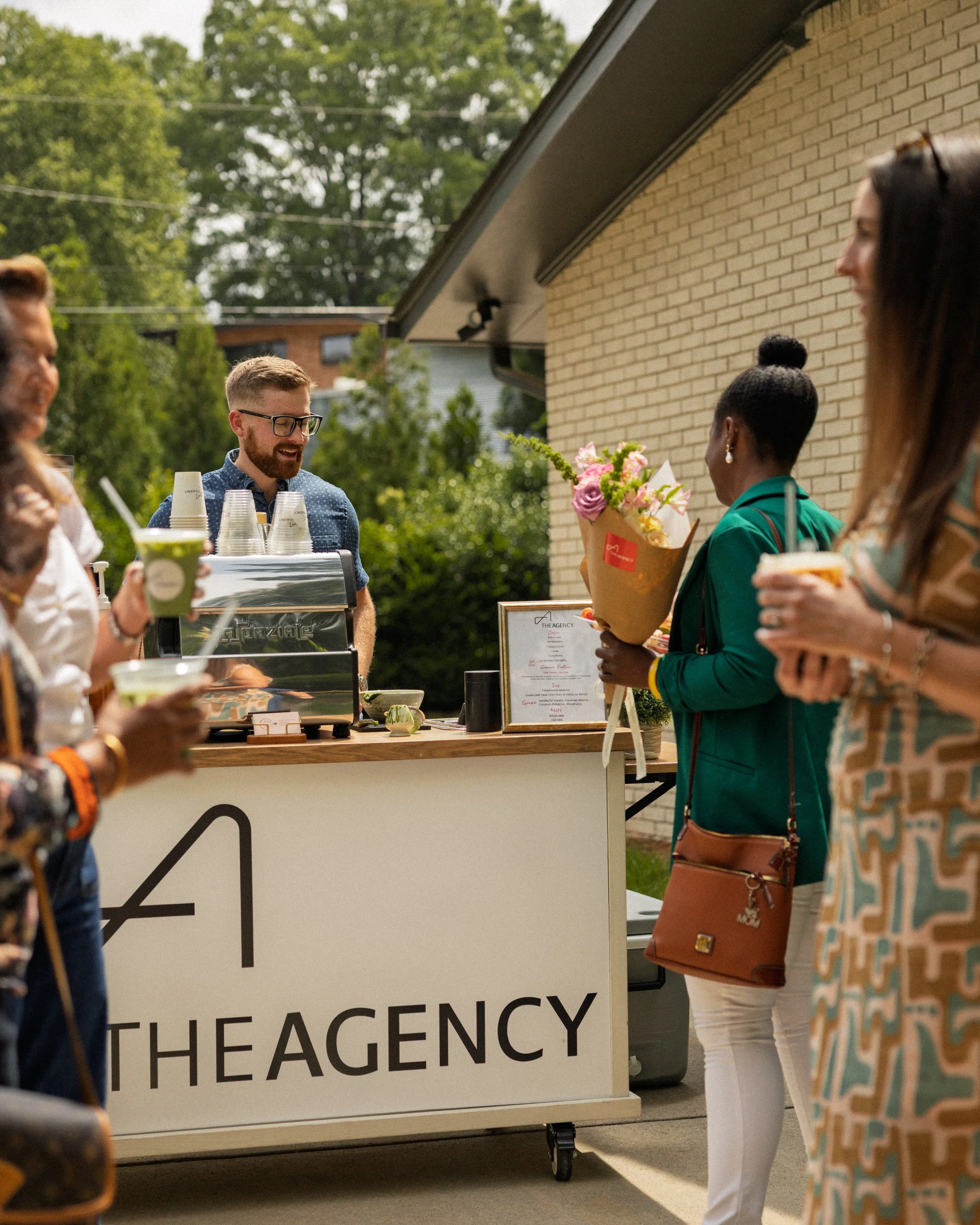 A guest holding flowers is looking at the custom branded menu to determine what drink to order