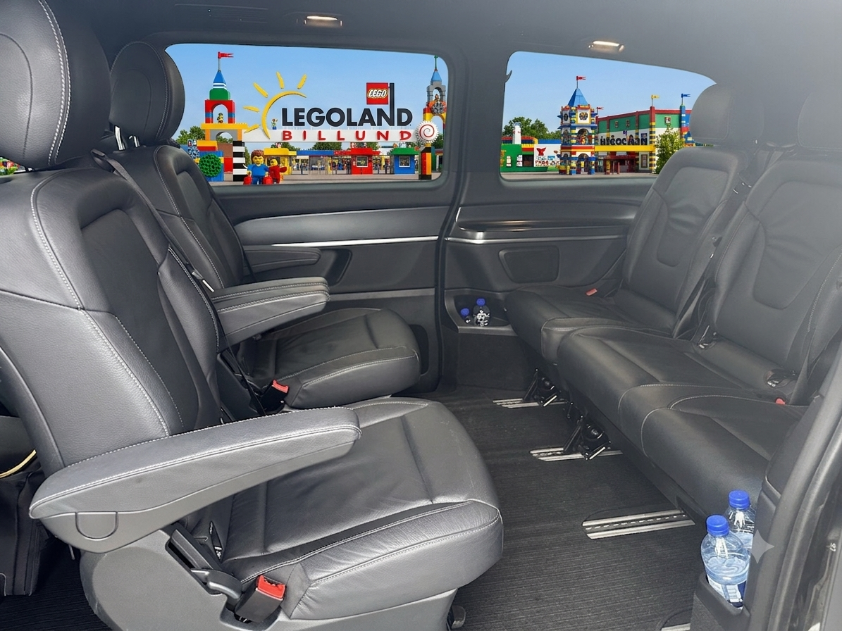 Interior of a Luxury Mercedes vehicle with three rows of black leather seats, blue water bottles in cup holders, and a view of LEGOland Billund park with LEGO structures and characters through the windows.