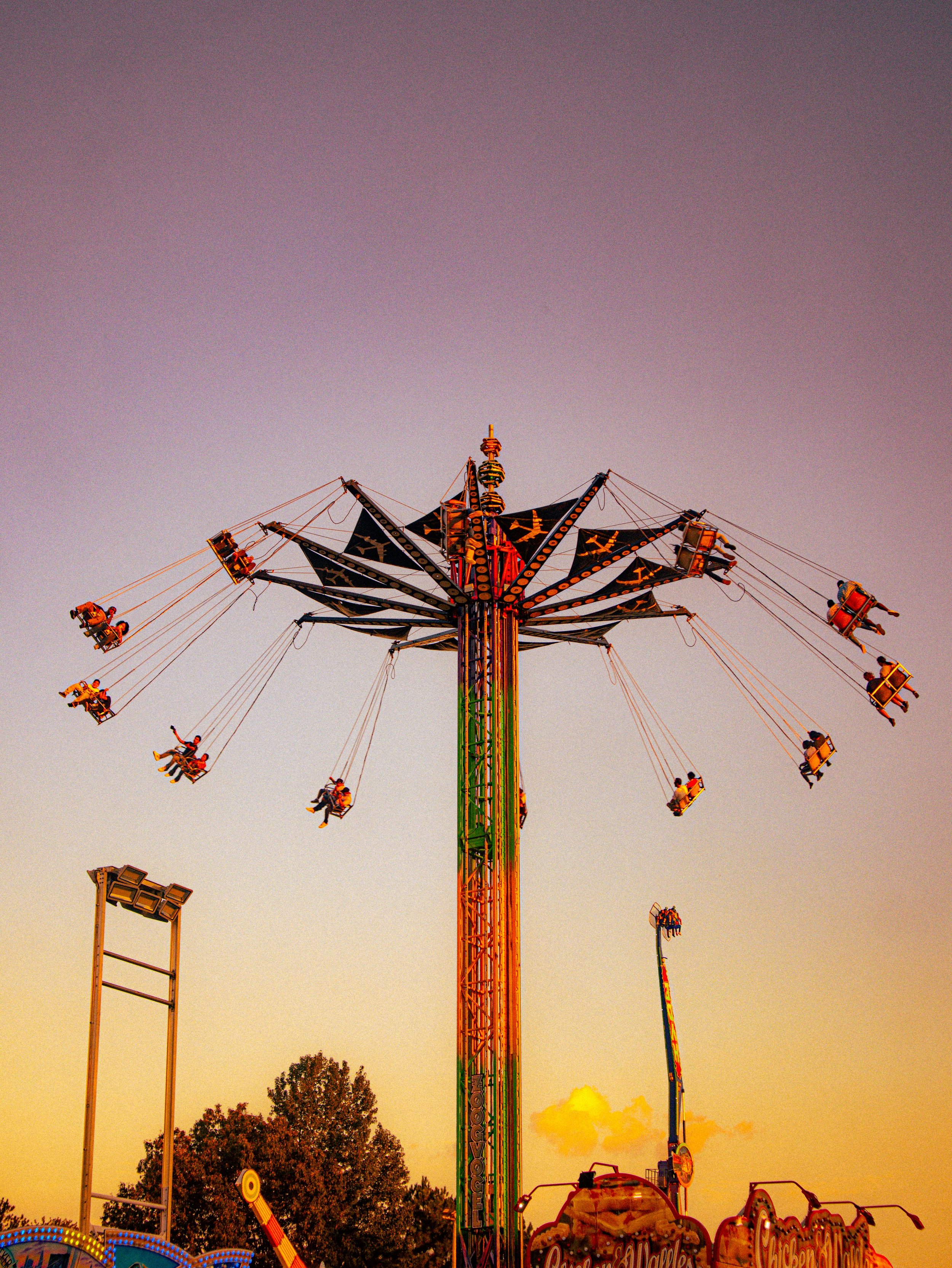 A colorful swing ride at Legoland Billund resort, with multiple swings occupied by riders, set against a sunset sky.