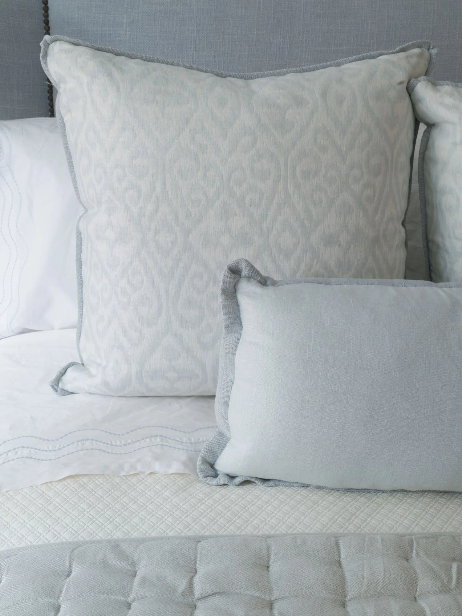 New York City bedroom interior design by Elizabeth Hartz Interior Design featuring layered blue and white bedding, tailored pillows, and soft textured linens.