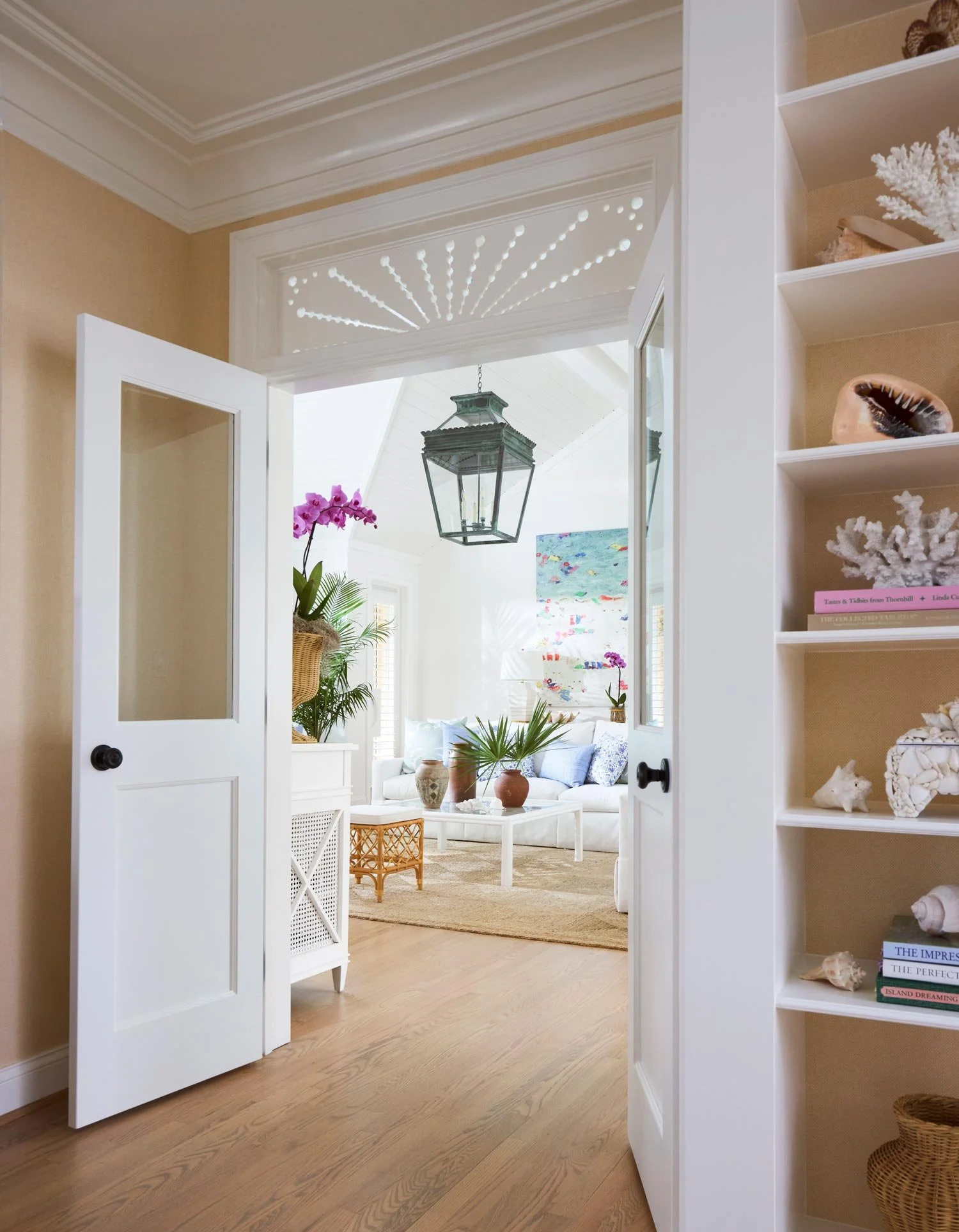 Elizabeth Hartz interior designer Virginia Beach oceanfront home entry view through double doors into a light-filled living room with coastal textures, blue accents, and Palm Beach–inspired design