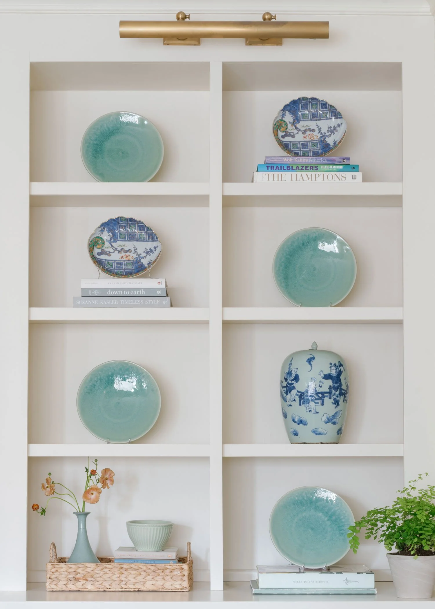 New York City apartment living room built-in shelving styled by Elizabeth Hartz Interior Design featuring curated blue and green ceramics, decorative plates, collected books, and layered accessories in a classic, southern-inspired interior.